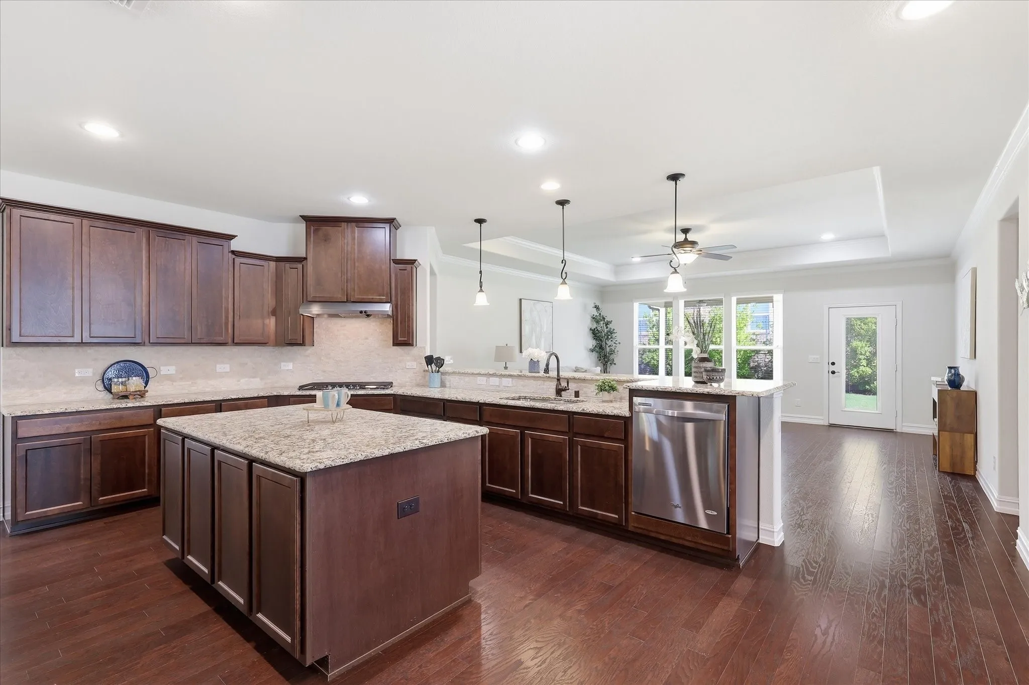 Gourmet kitchen featuring a central island, rich wood cabinetry, stainless steel appliances, granite countertops, and wood-finish flooring