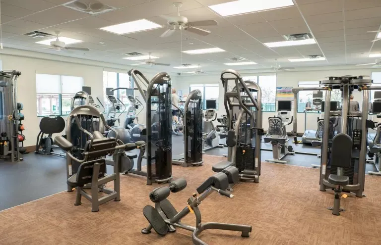Spacious fitness center featuring a variety of strength training equipment, cardio machines, ceiling fans, recessed lighting, and large windows
