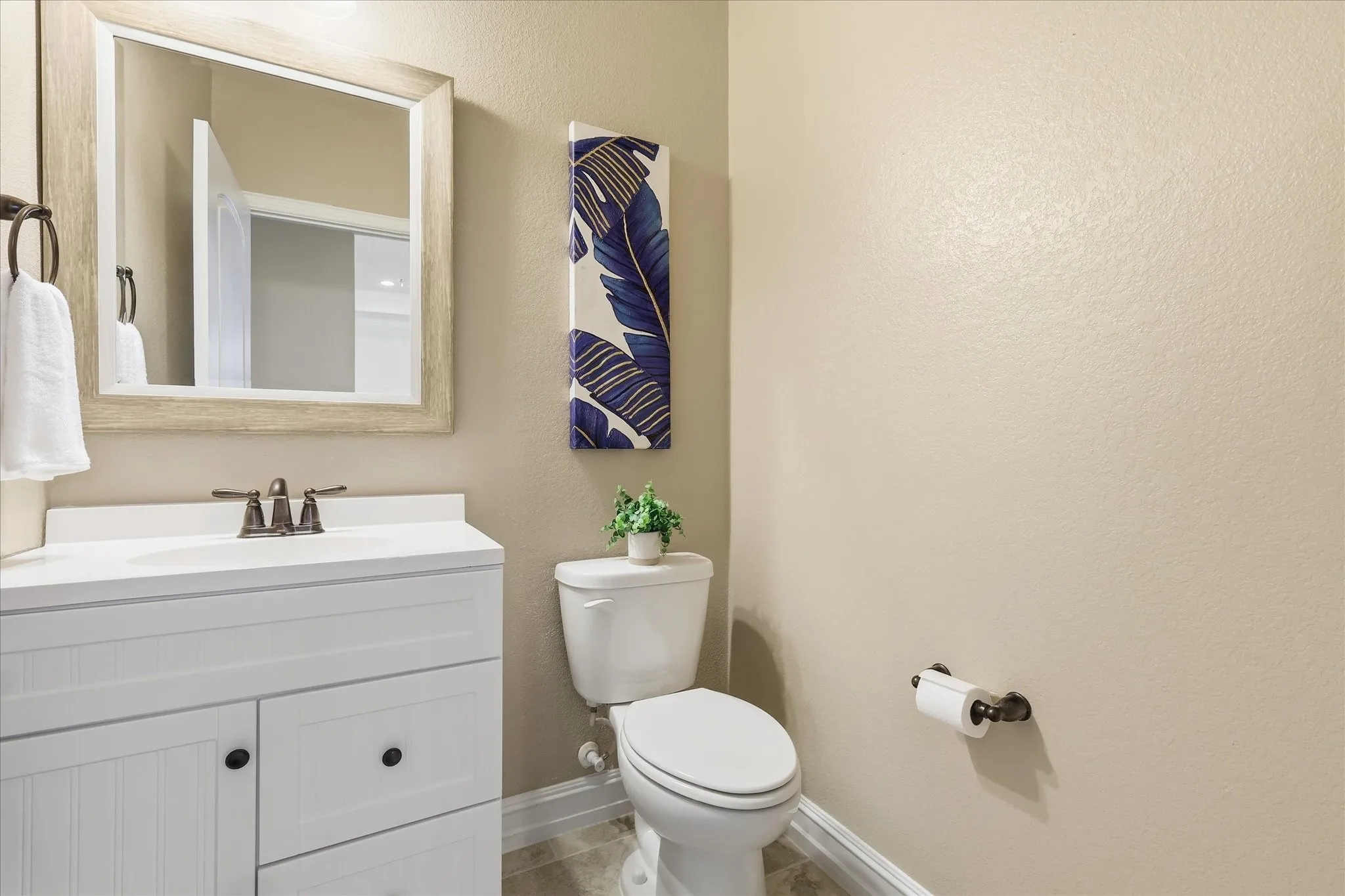 Powder room featuring a white vanity with paneling and dark hardware, a white countertop, and a bronze-finish faucet