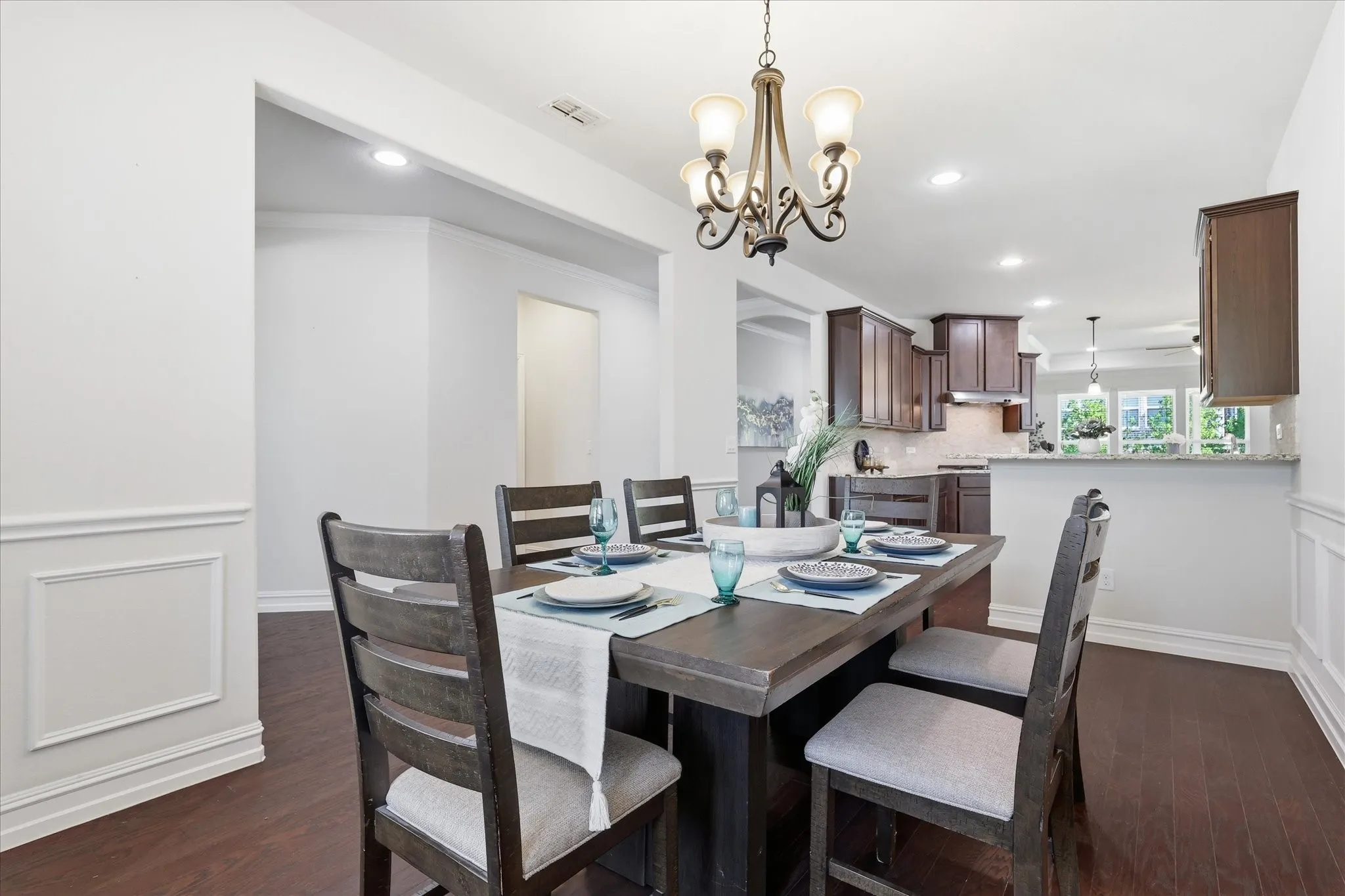 Dining area featuring wood-finish flooring, wainscoting, and an ornate chandelier
