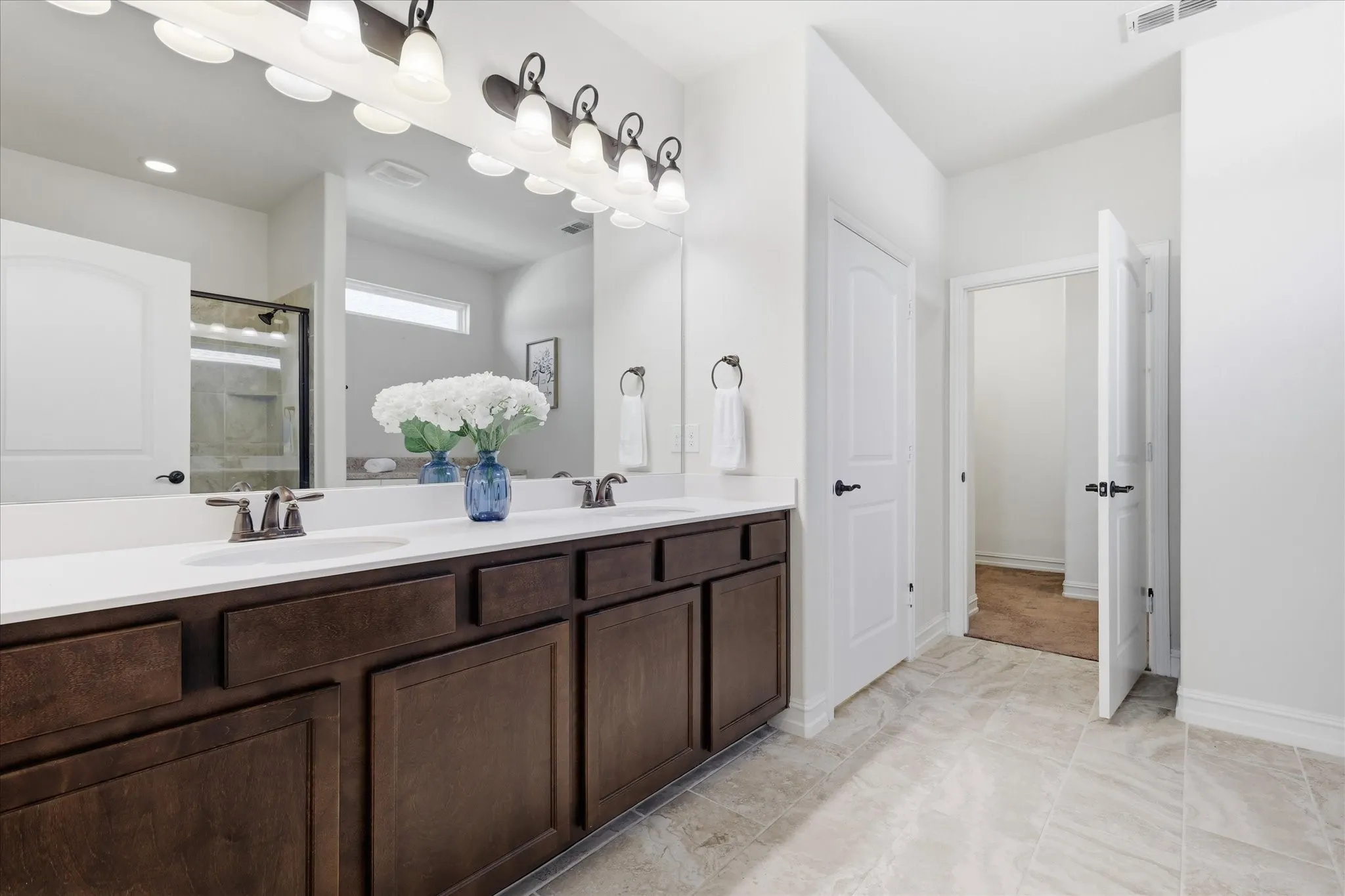 Primary Bathroom featuring a dual vanity with dark wood-finish cabinetry and white countertops