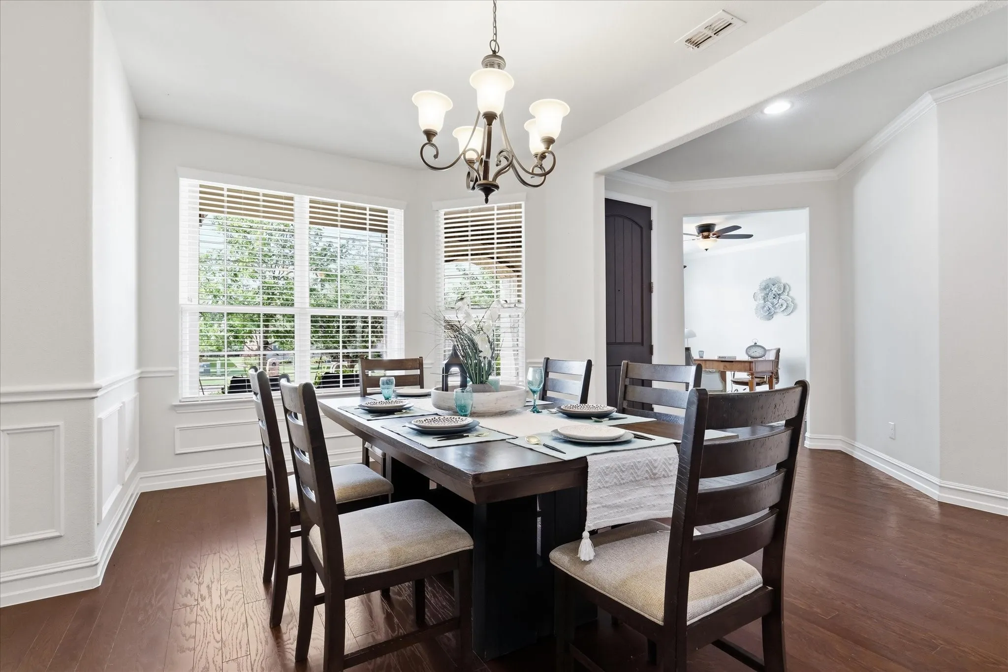 Bright dining area featuring wood-finish flooring, wainscoting, and crown molding