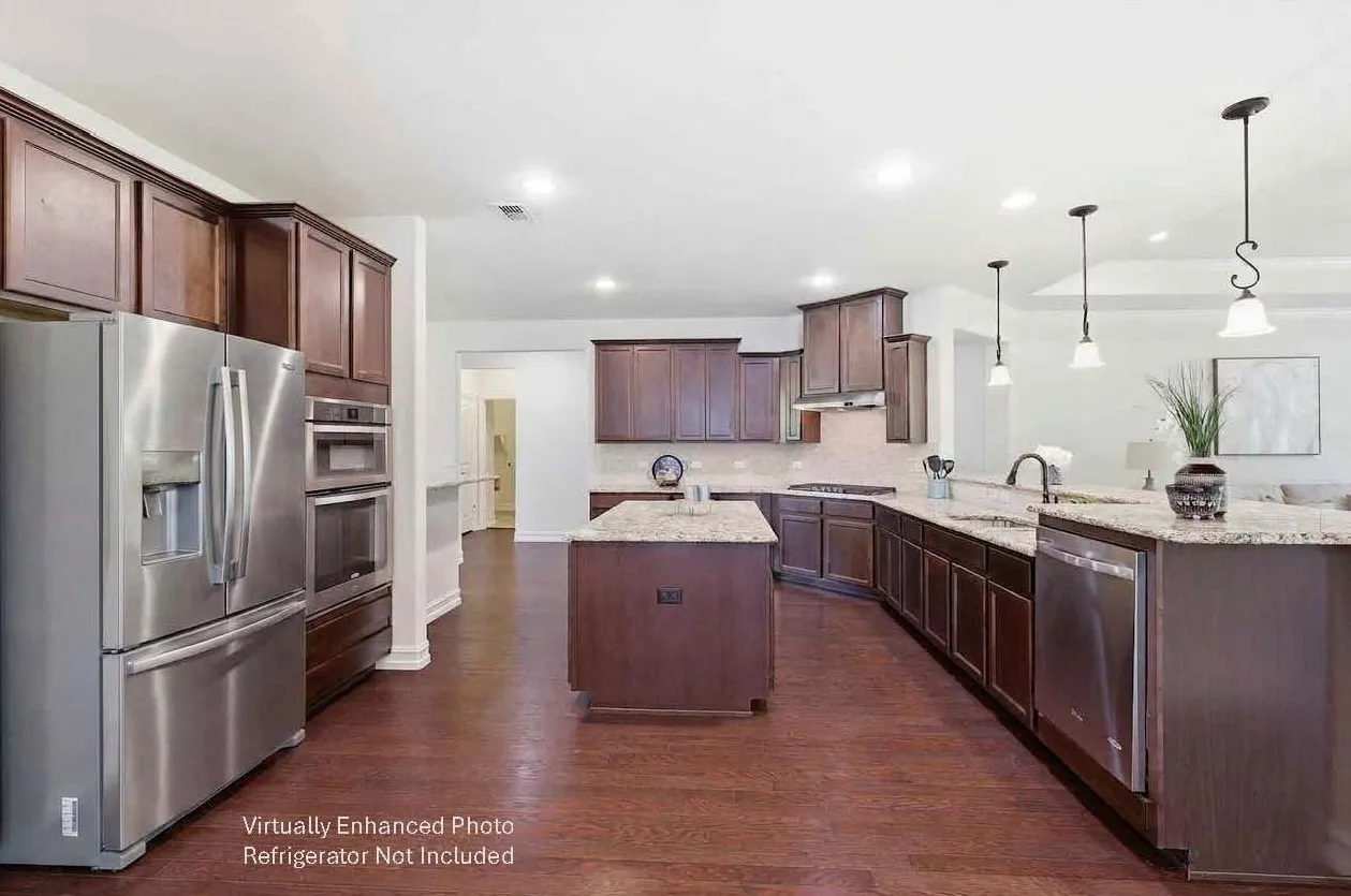 Spacious kitchen featuring dark wood cabinetry, light-toned granite countertops, stainless steel appliances, and wood-finish flooring - Refrigerator Not Included