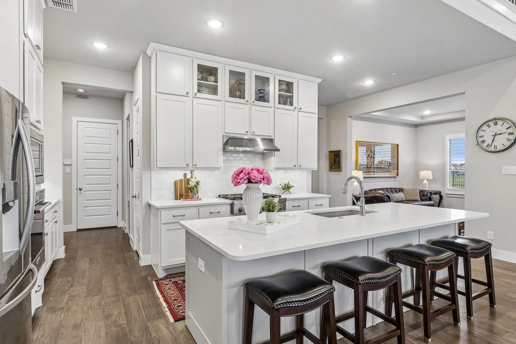 The gourmet kitchen features a large center island with seating, KitchenAid six-burner range, quartz counters, soft-close cabinetry, built-in oven and microwave, and walk-in pantry.
