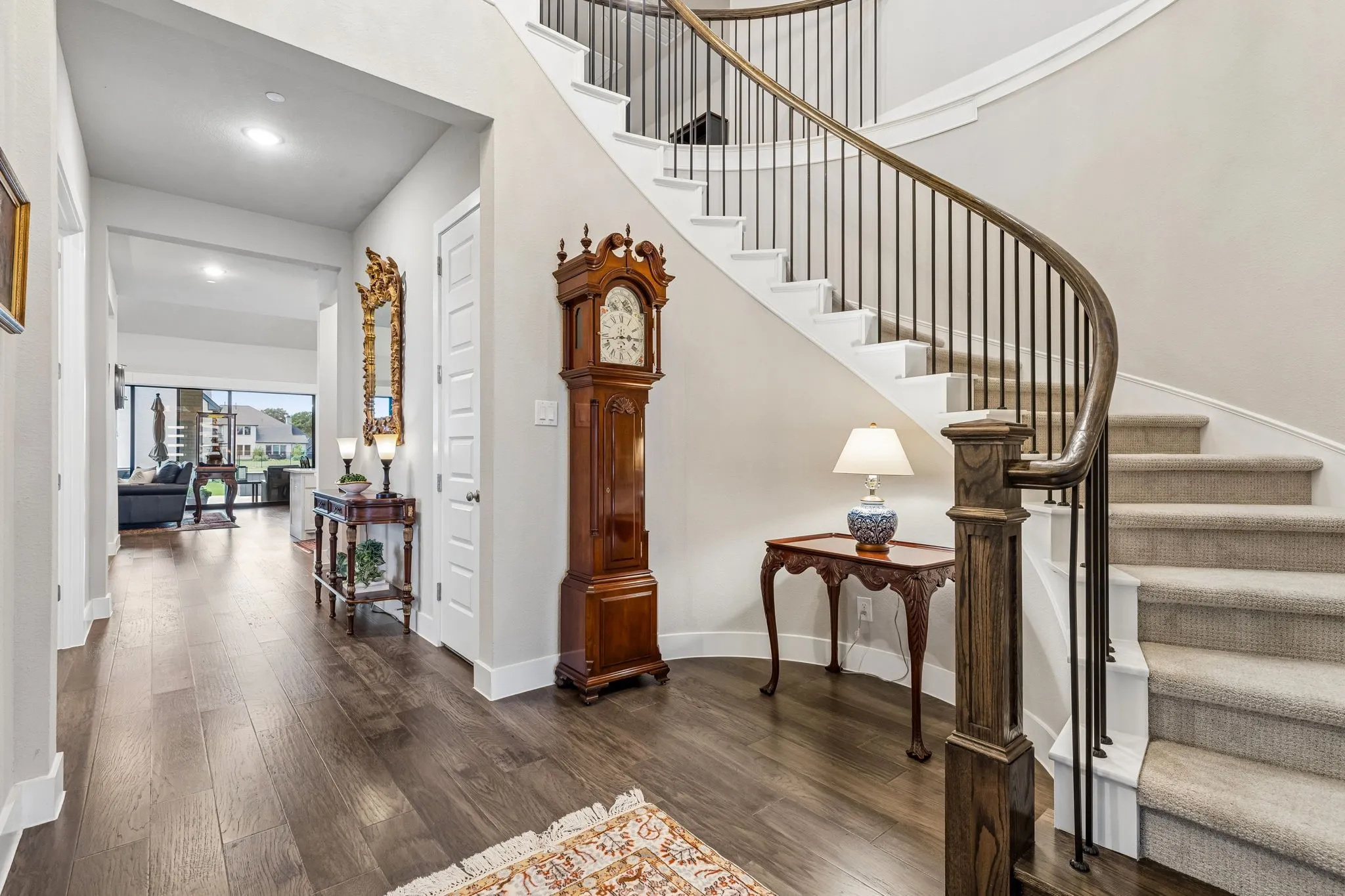 A two-story foyer with a curved staircase opens to a thoughtfully designed floor plan with soaring ceilings, gorgeous hardwood floors, quartz countertops, plantation shutters, and solid-core doors throughout.