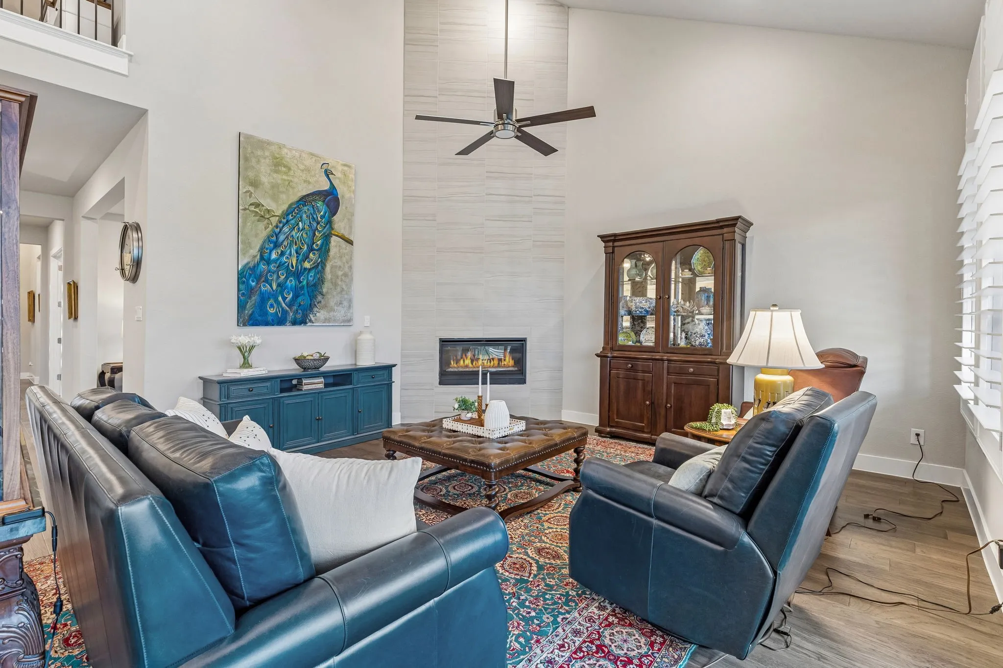 The grand living room features vaulted ceilings, a dramatic floor-to-ceiling corner fireplace, and a wall of windows overlooking the beautifully landscaped backyard.