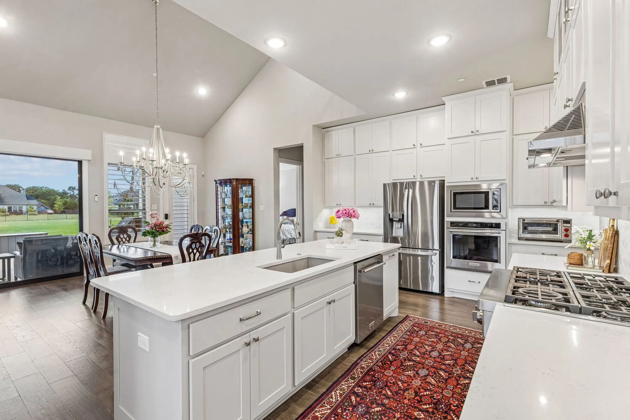 The chef's kitchen flows seamlessly to the spacious breakfast room with vaulted ceilings and sliding doors to the large covered patio with sun-blocking electric shades.