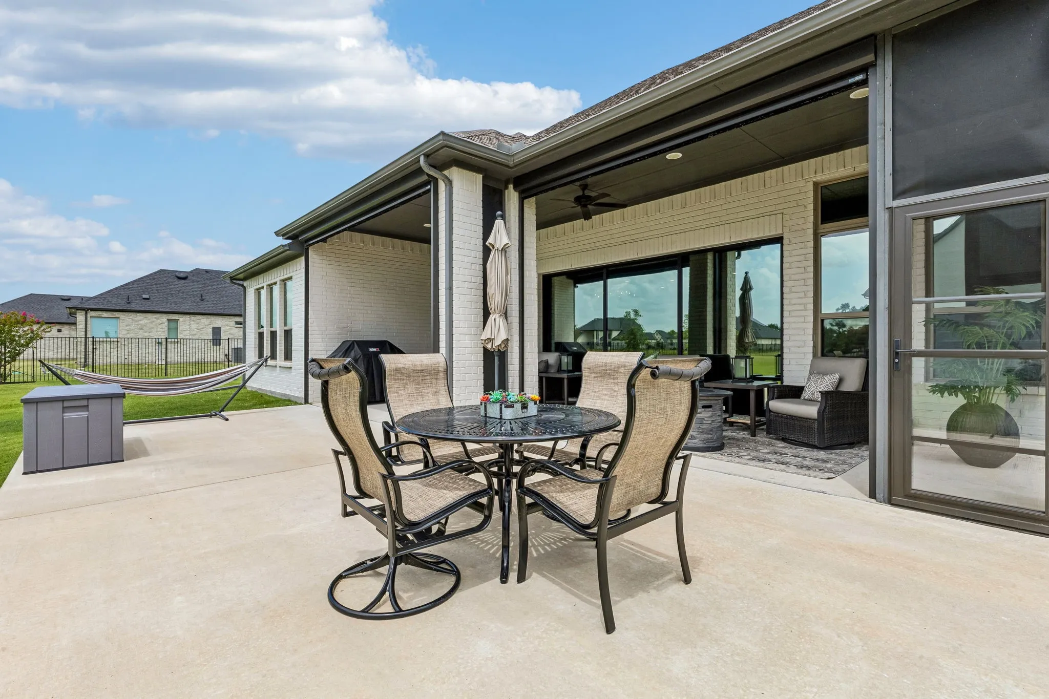 Large covered patio with sun-blocking electric shades overlooking the expansive backyard.