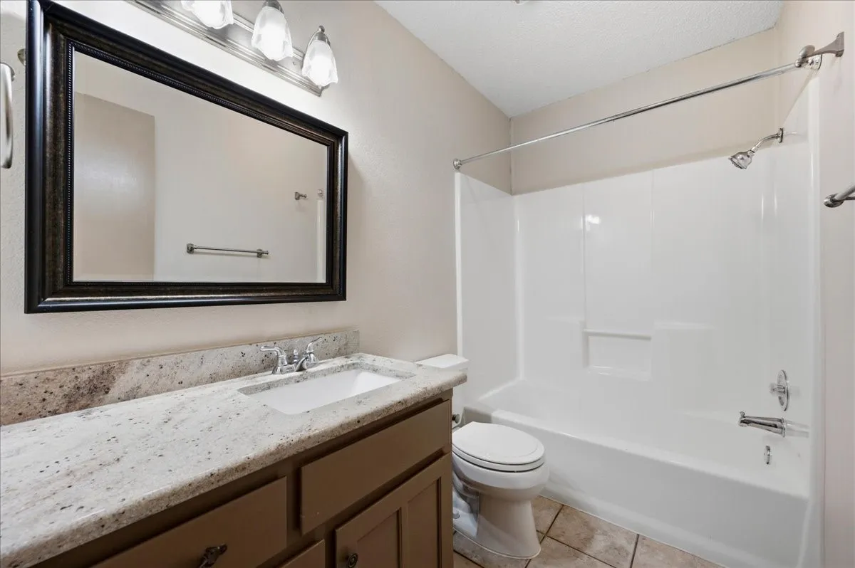 Bathroom featuring a vanity with a white speckled countertop, undermount sink, and chrome faucet