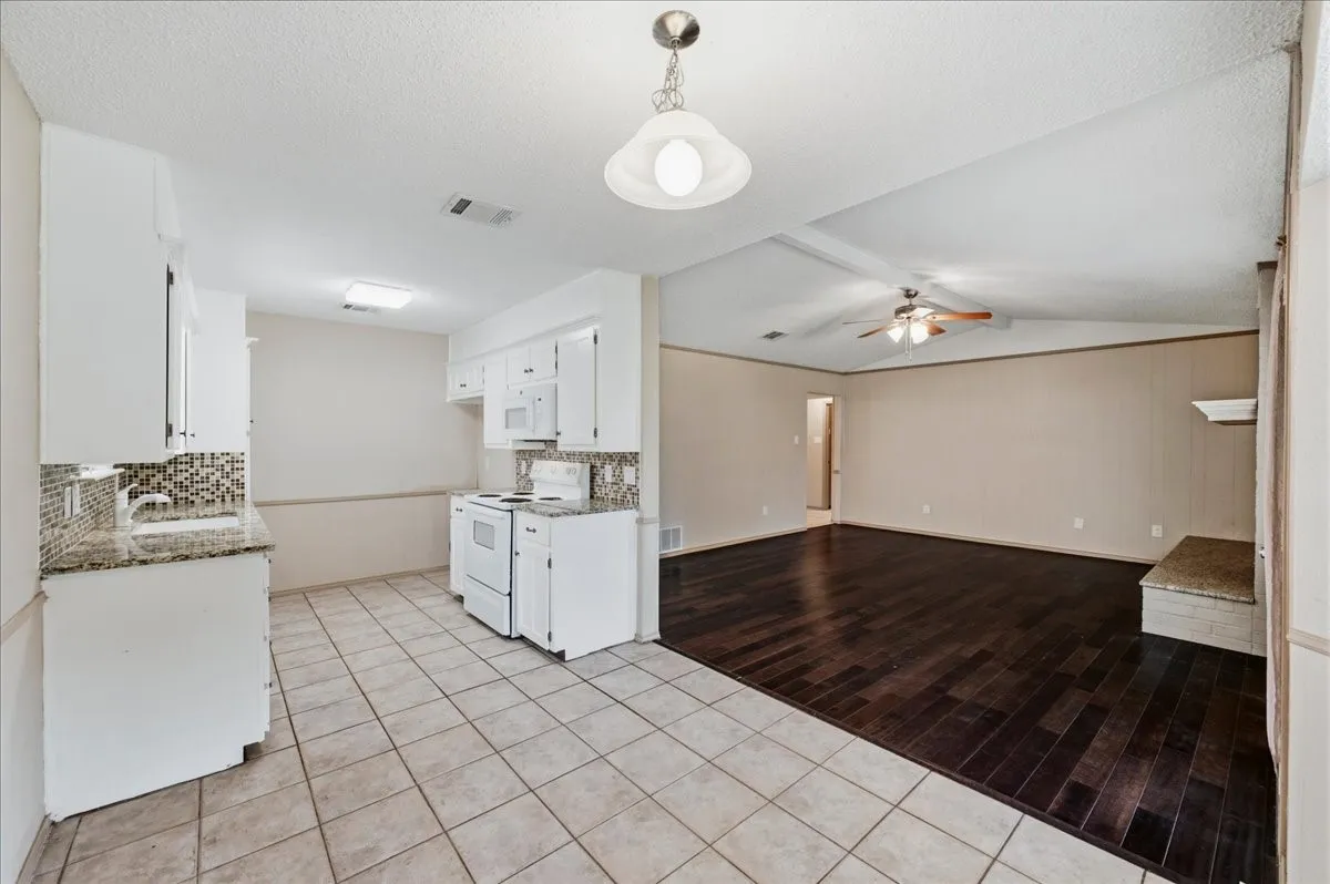Kitchen with white cabinetry, granite-finish countertops, and a mosaic tile backsplash