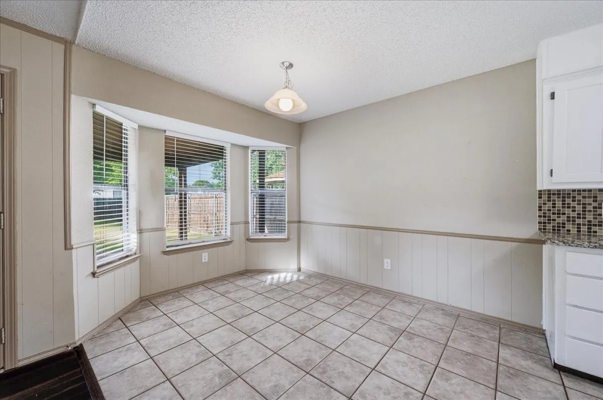 Dining area featuring a bay window, ceramic tile flooring, beadboard wainscoting, and a ceiling-mounted light fixture