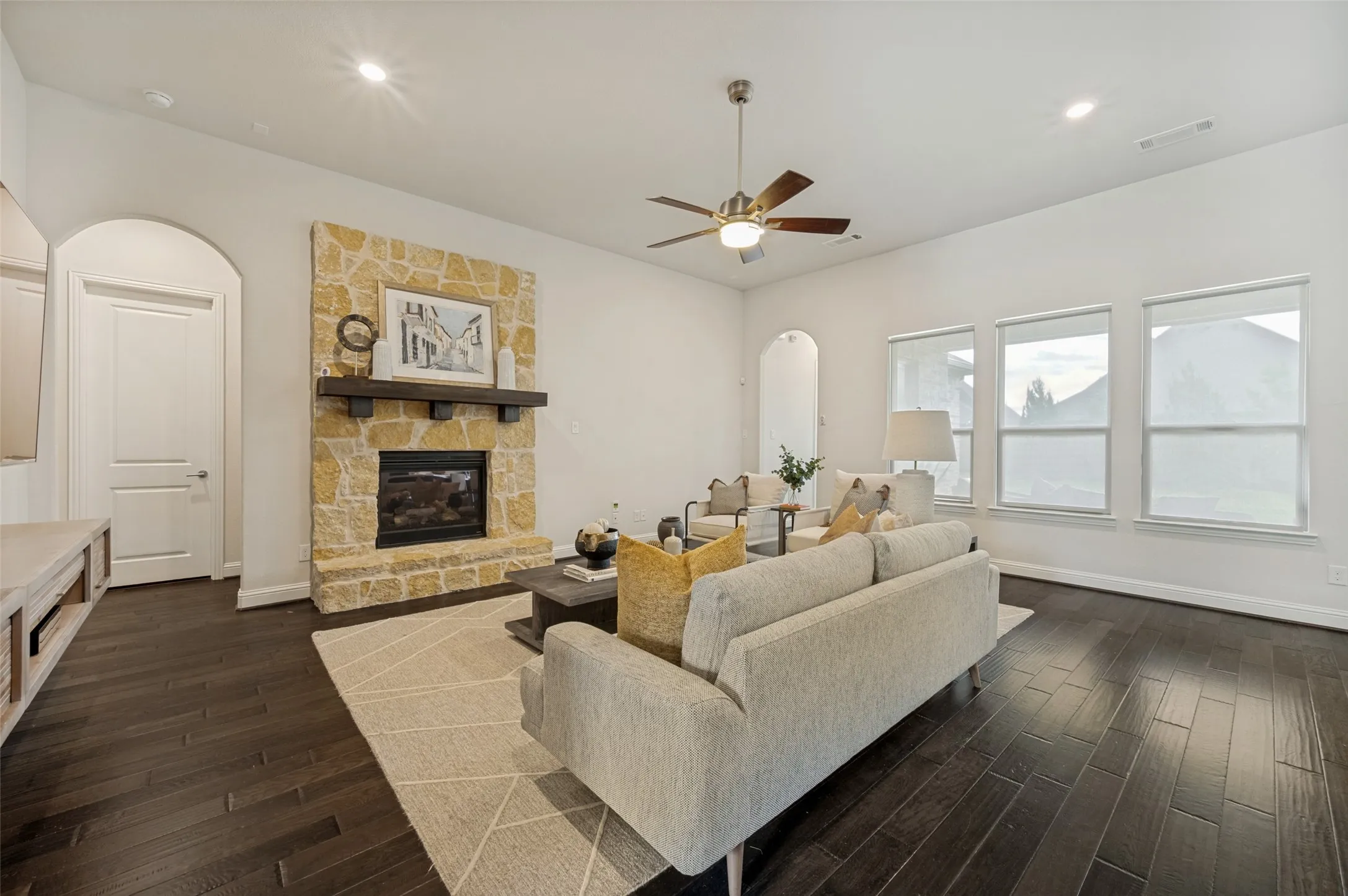 Bright and inviting living area perfect for entertaining, highlighted by a stunning stone fireplace and expansive windows.
