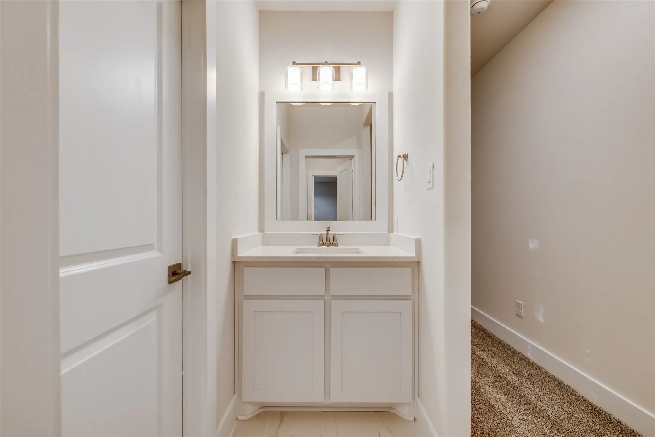 Powder room featuring a single vanity with a light-toned countertop, integrated sink, and white cabinetry