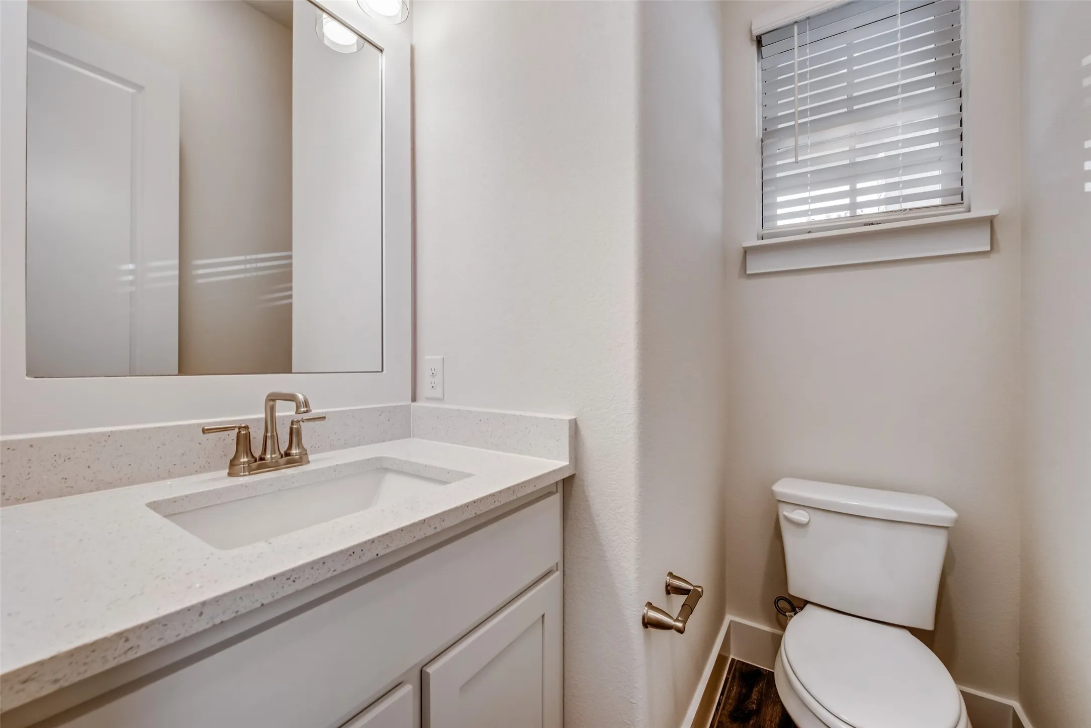 Bathroom vanity featuring a light-toned countertop with an integrated sink and brushed nickel faucet