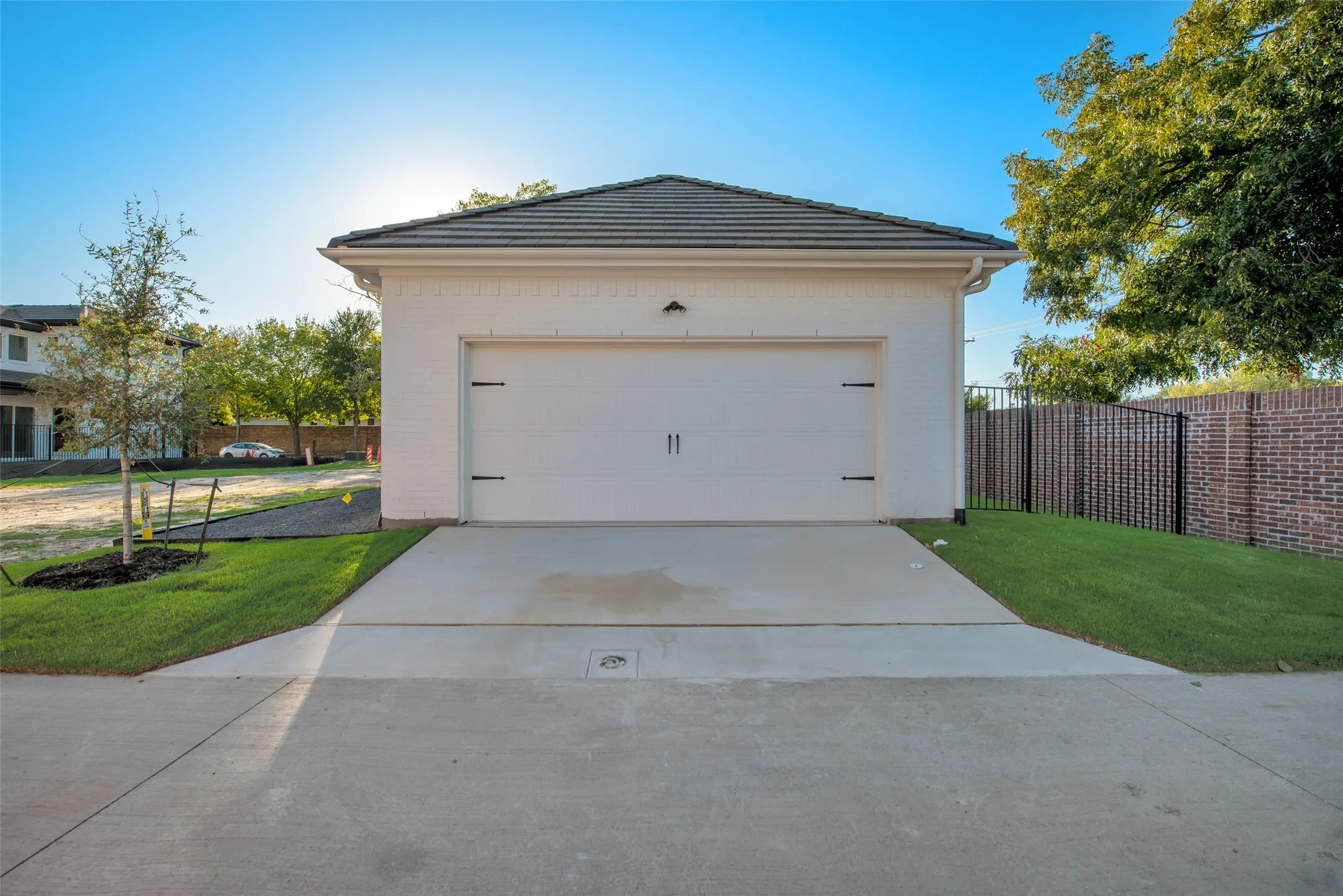 Detached garage featuring a white painted brick exterior, a single overhead door with decorative hardware, and a dark tile roof