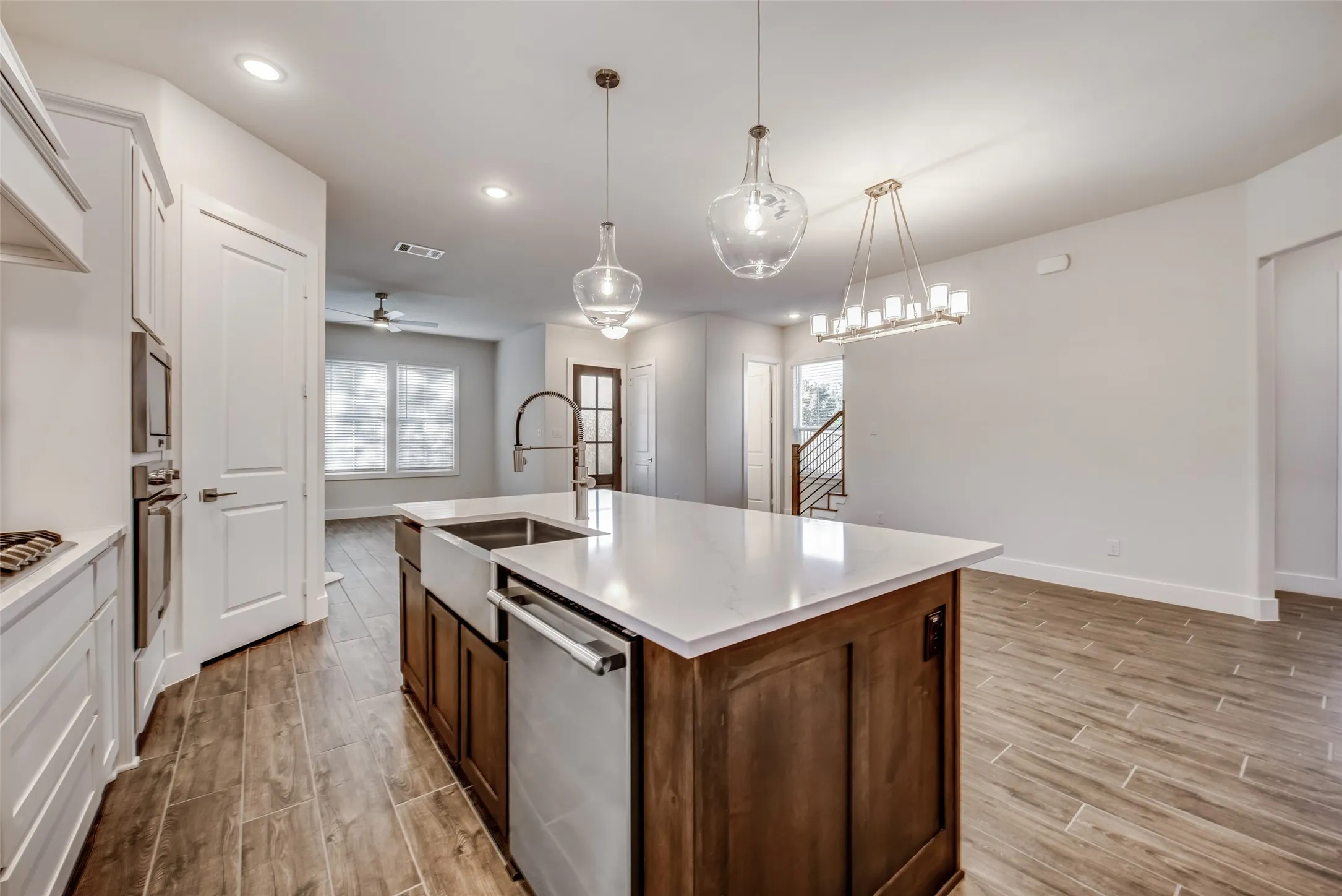 Kitchen island featuring a farmhouse sink, stainless steel dishwasher, and a light-toned countertop