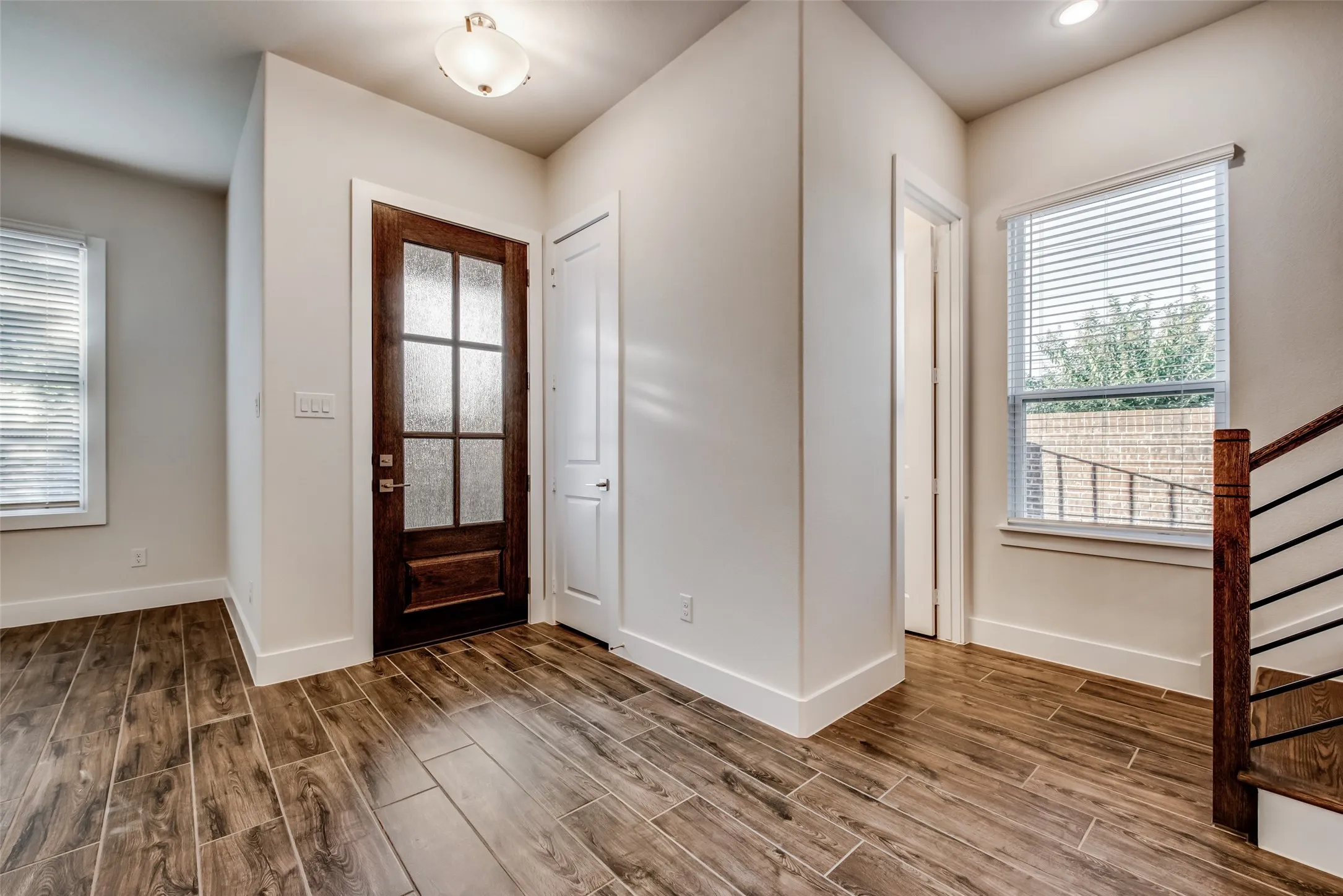 Entryway featuring wood-finish tile flooring, a paneled wood-frame door with frosted glass inserts, a flush-mount ceiling light fixture, and white baseboards