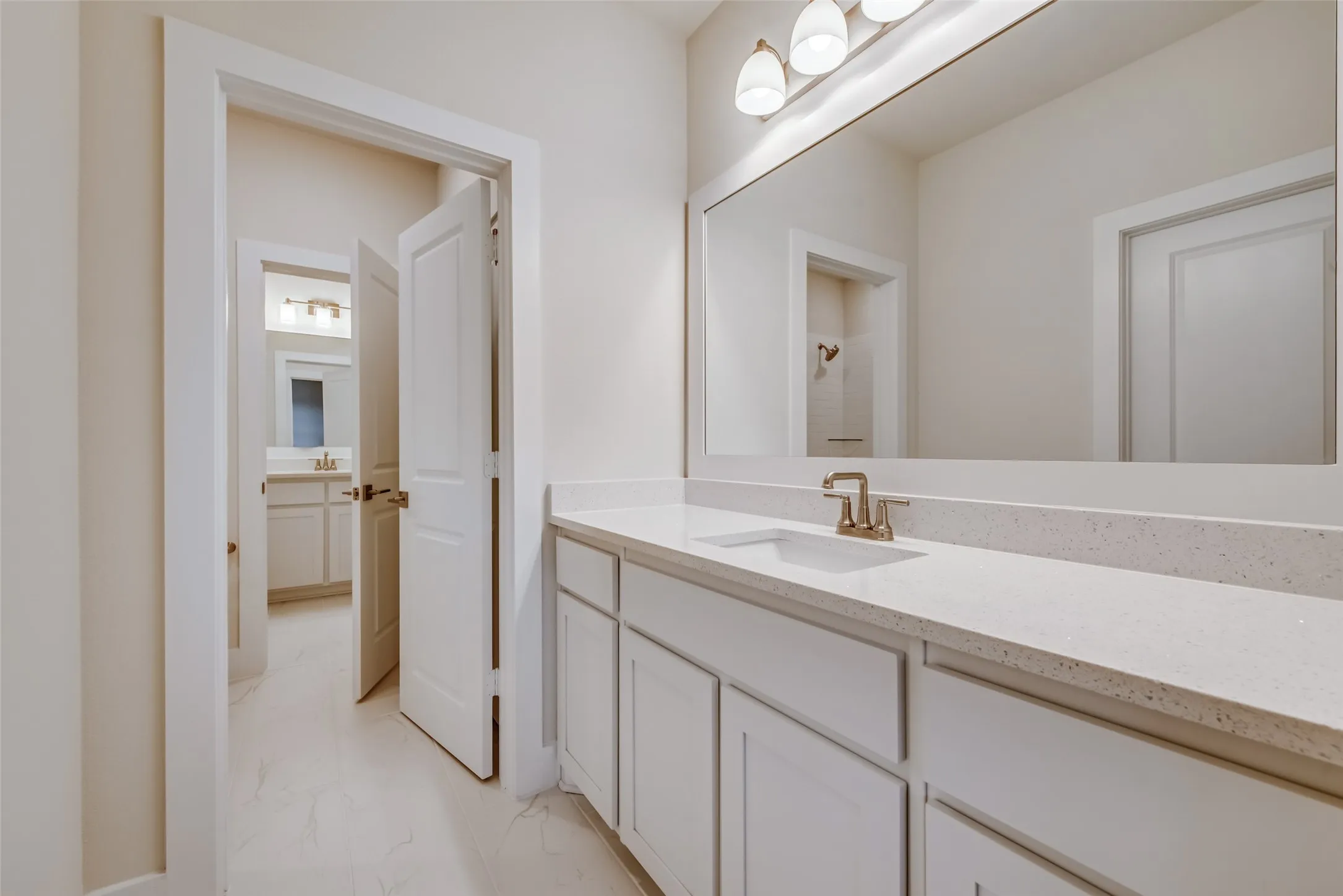 Bathroom featuring an extended vanity with a light-toned countertop, an undermount sink, and a framed mirror