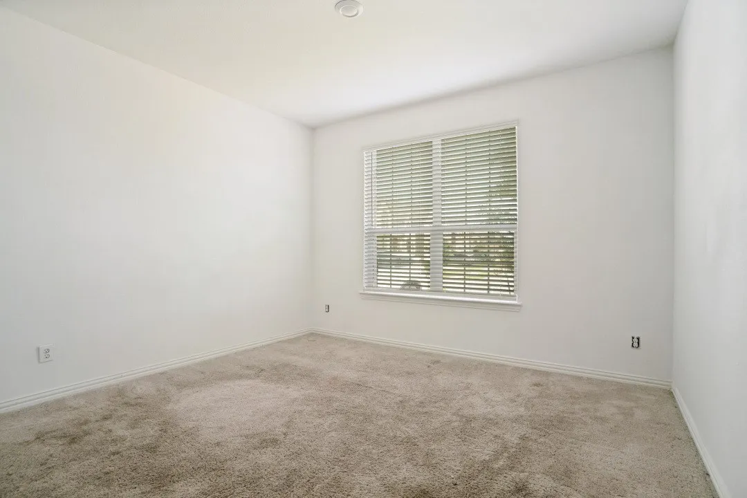 Carpeted room with a double window featuring blinds
