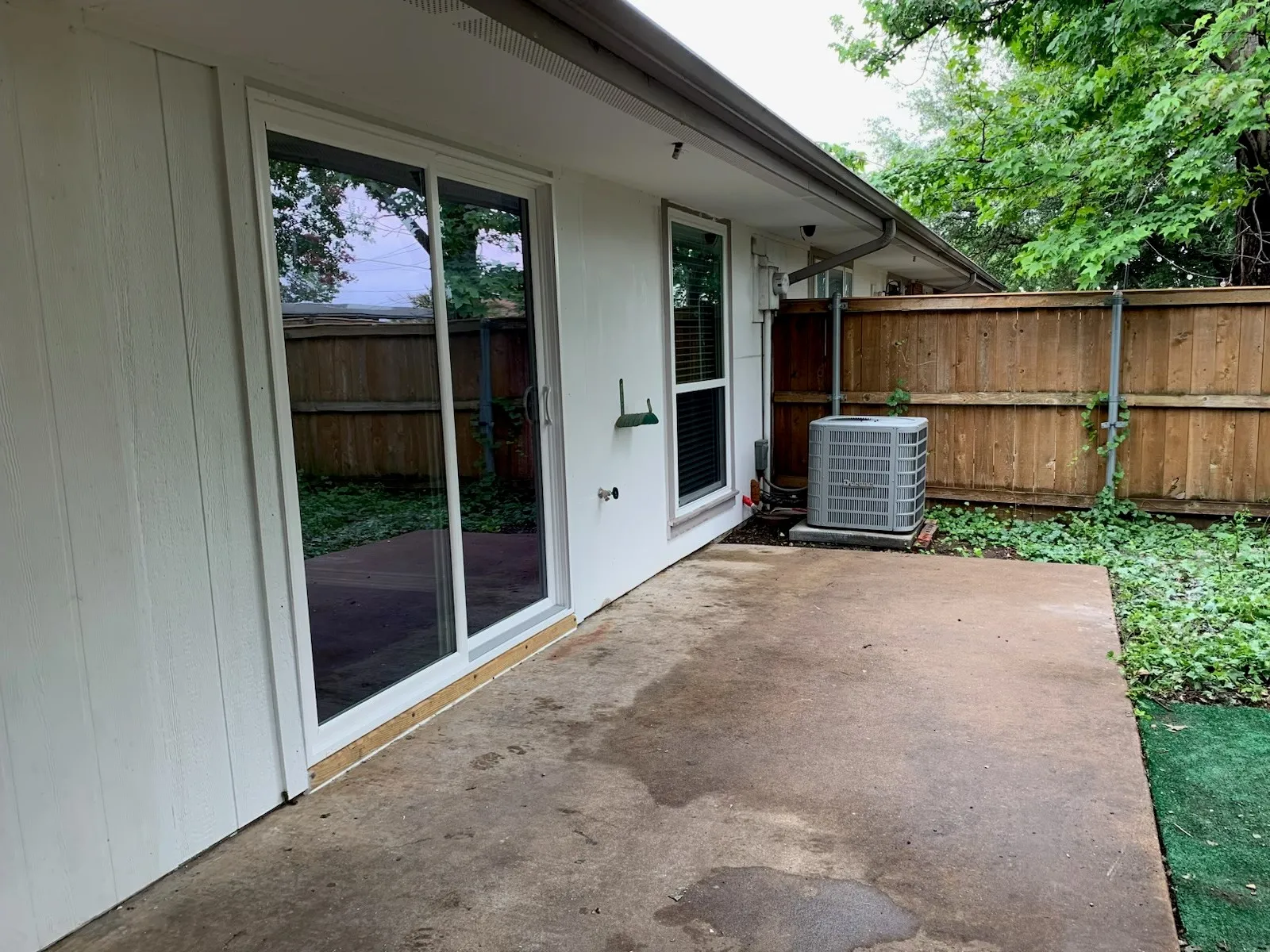 Exterior patio featuring a concrete surface, sliding glass door, and a wood privacy fence