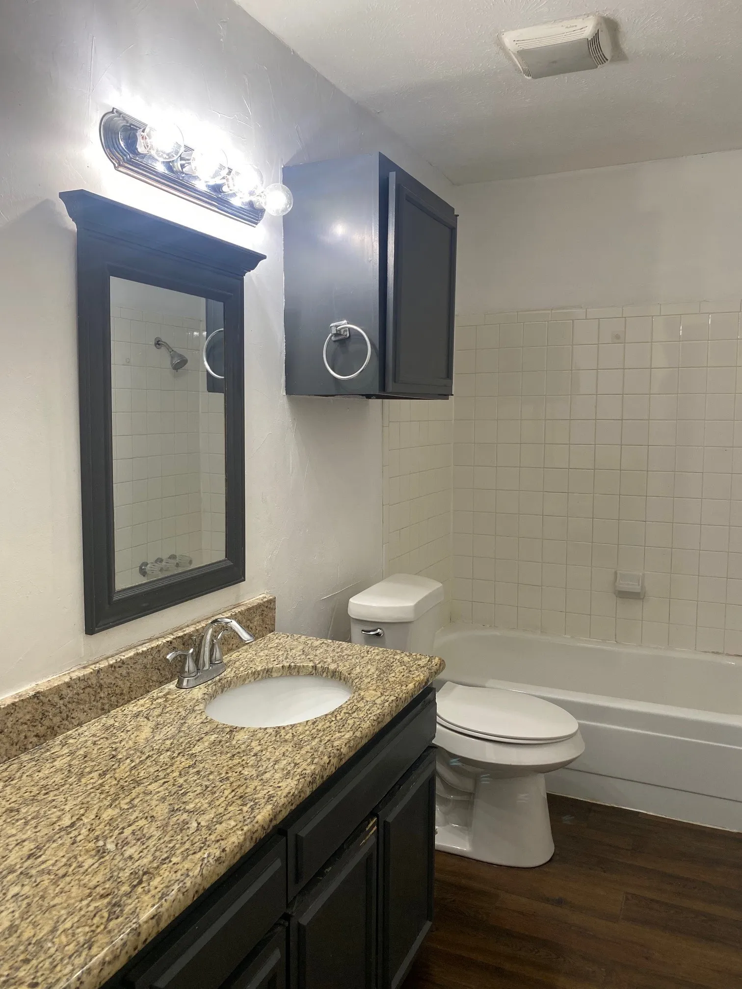 Bathroom with vanity, dark wood-style flooring, and shower / bath combination