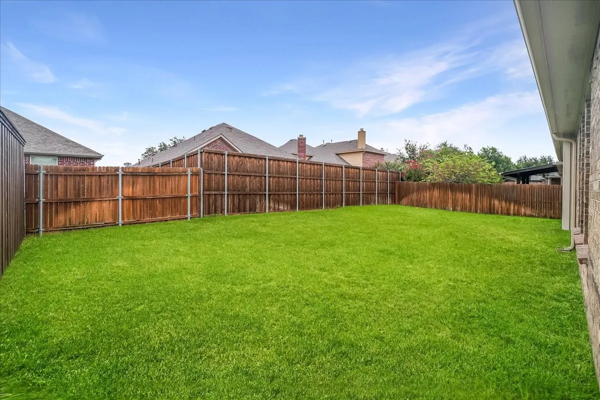 Expansive green lawn enclosed by tall wood fencing