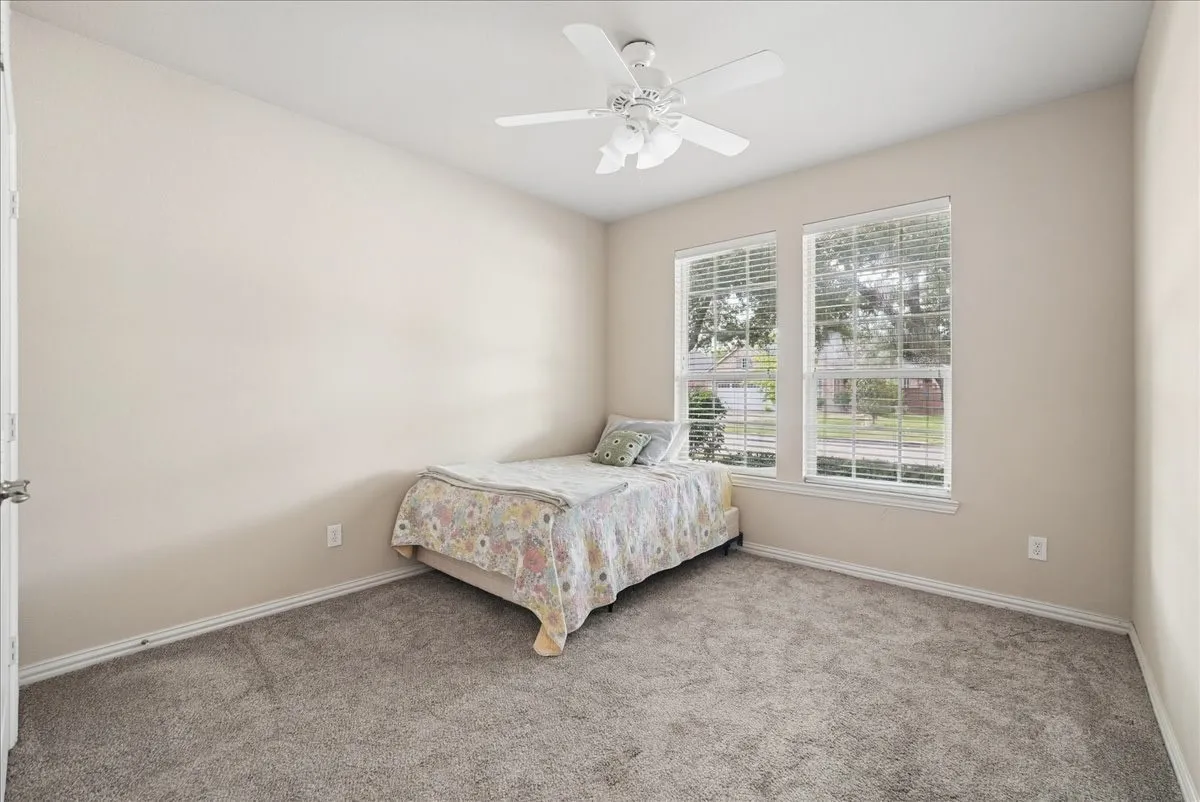 Carpeted room featuring dual windows with blinds, a ceiling fan, and neutral wall tones
