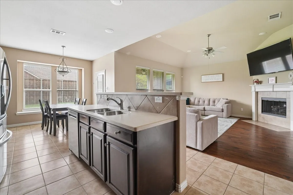 Kitchen featuring a double basin sink, dark wood-finish cabinetry, and light-toned countertops