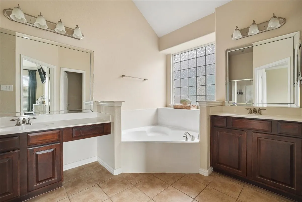 Bathroom featuring a corner soaking tub with a privacy glass block window