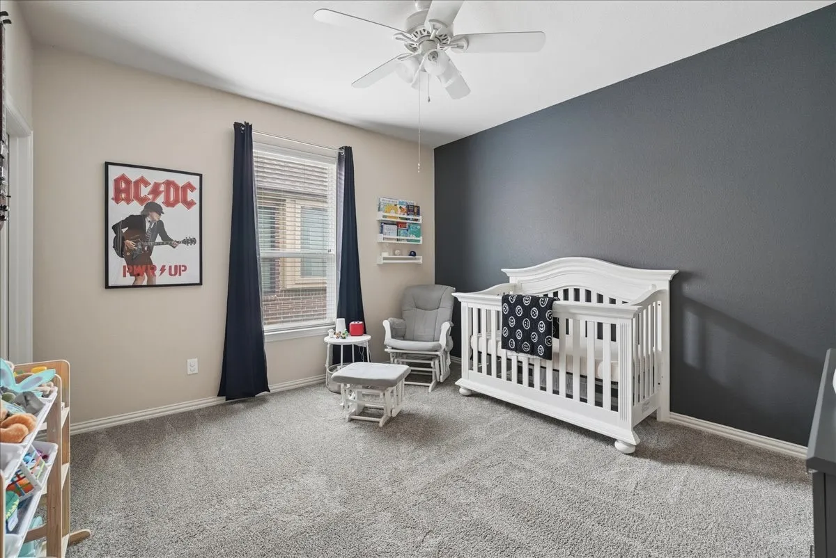 Spacious room featuring neutral carpeting, a dual-tone wall treatment with a prominent accent wall, and a ceiling fan with integrated lighting