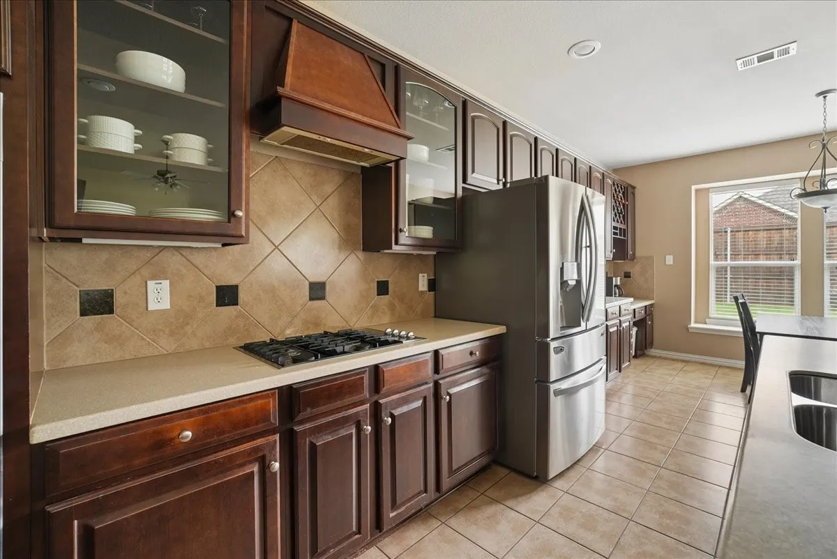 Kitchen with dark wood cabinetry, light countertops, and a tile backsplash