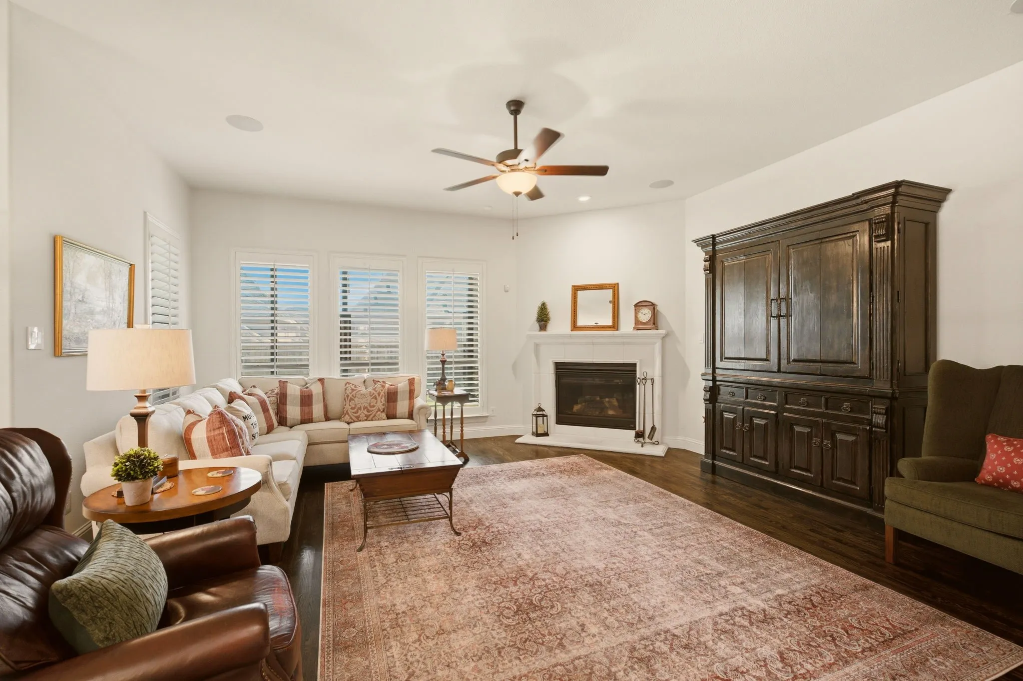 A central feature of the living room is the gas log fireplace, framed by a limestone surround, adding warmth & architectural interest while anchoring the expansive space. This inviting gathering area seamlessly blends expanse for multiple furniture pieces with comfort, making it equally suited for cozy evenings at home or entertaining family & friends. The open design enhances the home's spacious feel while offering beautiful sightlines of the screened patio & backyard.