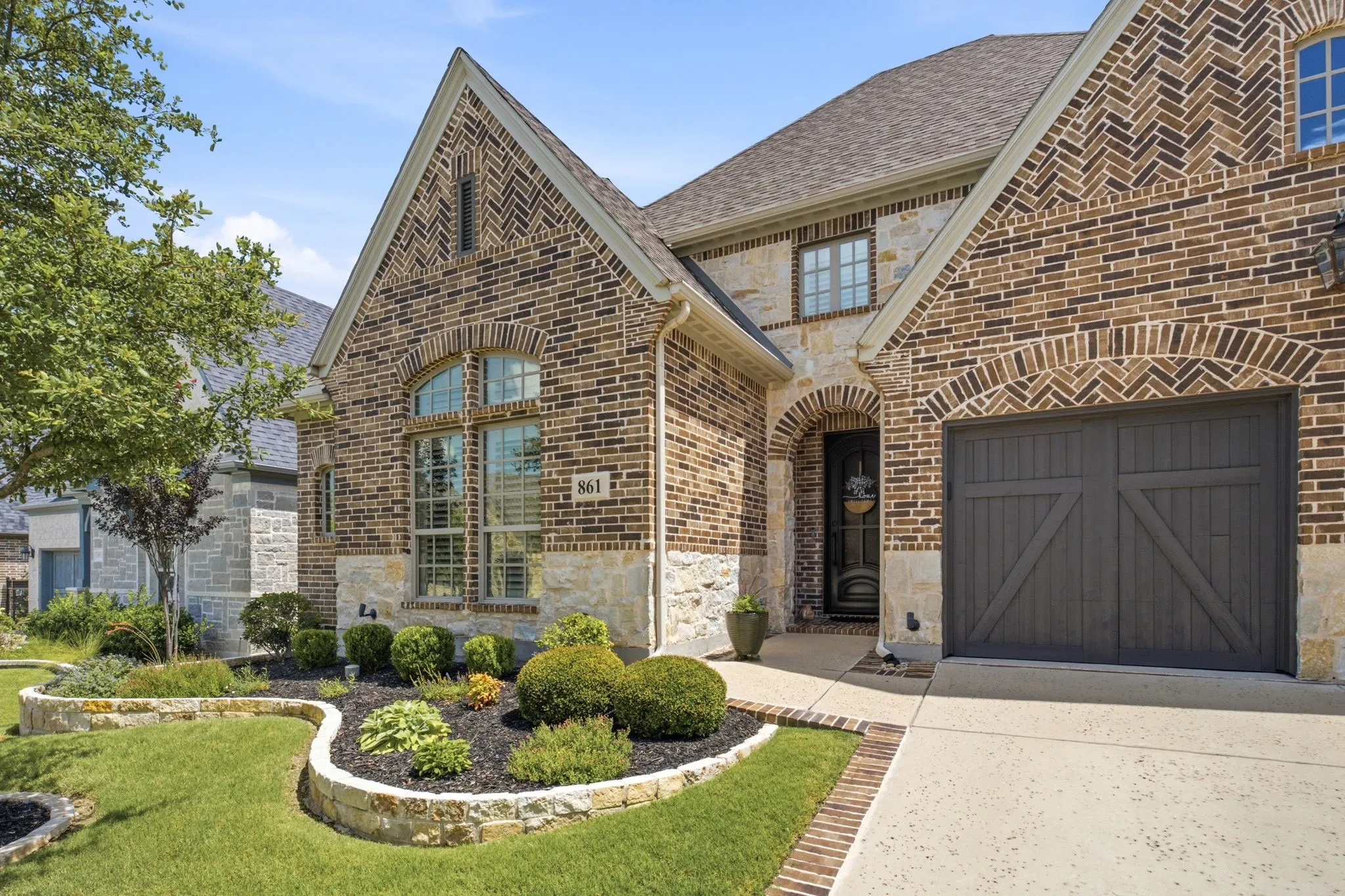 Charming curb appeal makes a welcoming first impression. From the stone accents around the landscaping & trees, brick pavers outlining the driveway, to the "Love That Door" custom wrought iron front door with Flemish glass that opens for air flow.