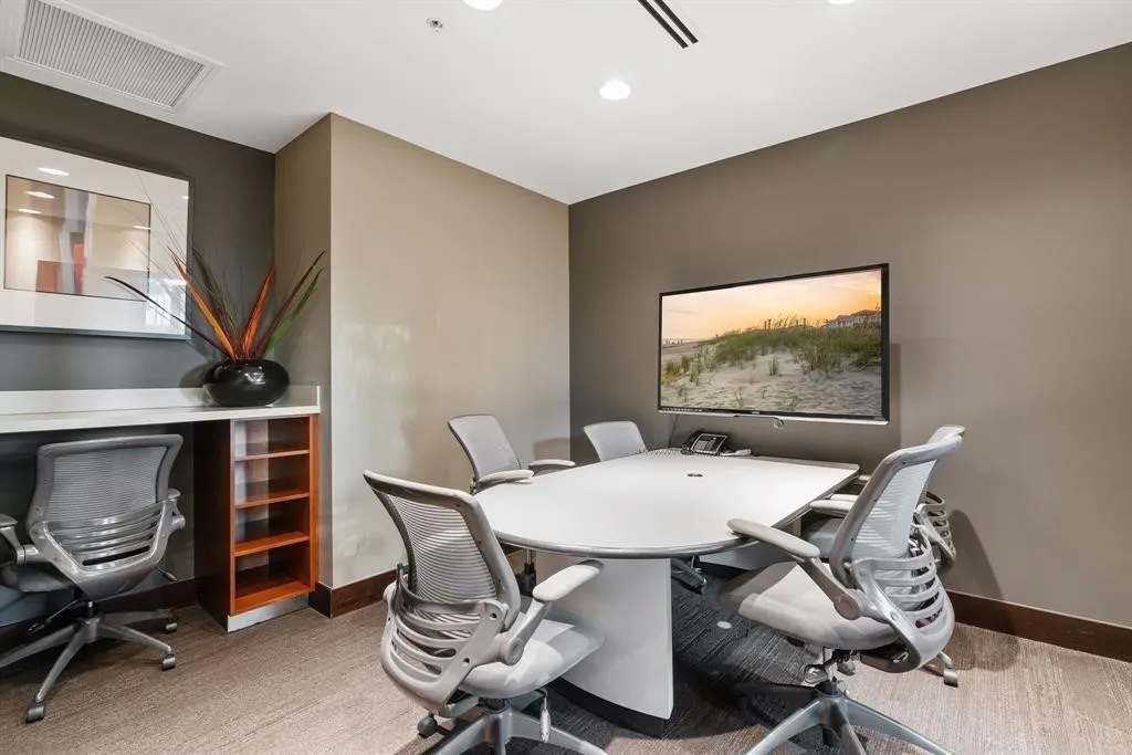 Meeting room featuring a large wall-mounted display, recessed ceiling lighting, and a built-in countertop with shelving