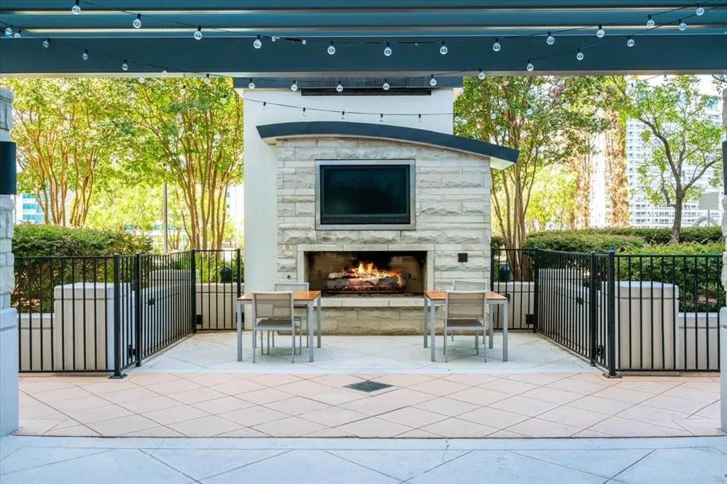 Outdoor patio featuring a stone-clad fireplace with a built-in media niche, string lighting, and a durable tile floor