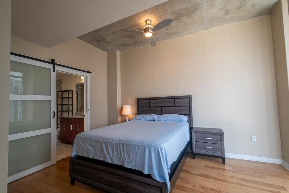 Bedroom featuring a concrete ceiling, a ceiling fan with integrated lighting, and wood-finish flooring