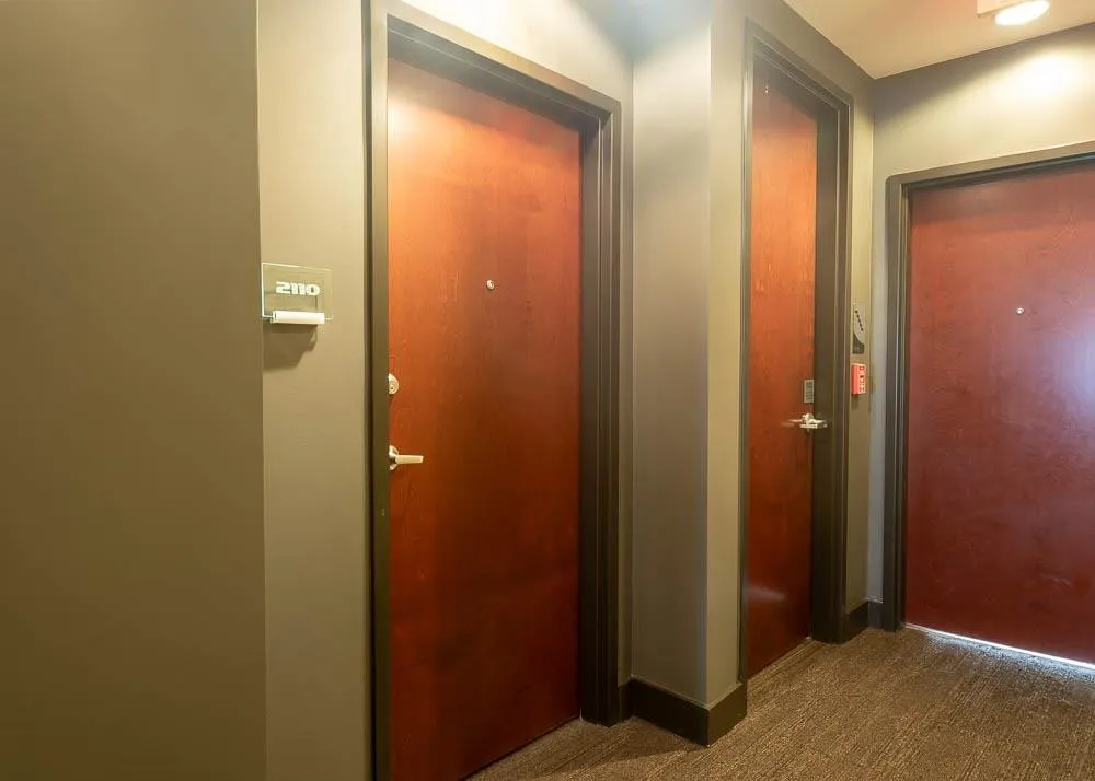 Hallway featuring doors with brushed nickel hardware, neutral-toned walls, and textured carpet flooring