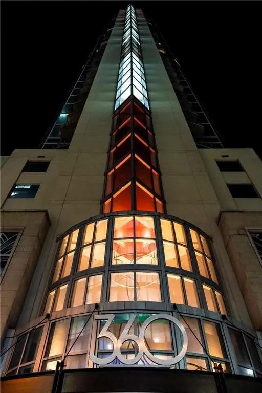 Modern high-rise building featuring a prominent glass-enclosed entrance with "360" signage