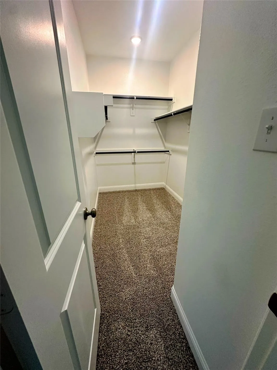 Walk-in closet with multi-level shelving, integrated hanging rods, recessed ceiling light, and plush carpet