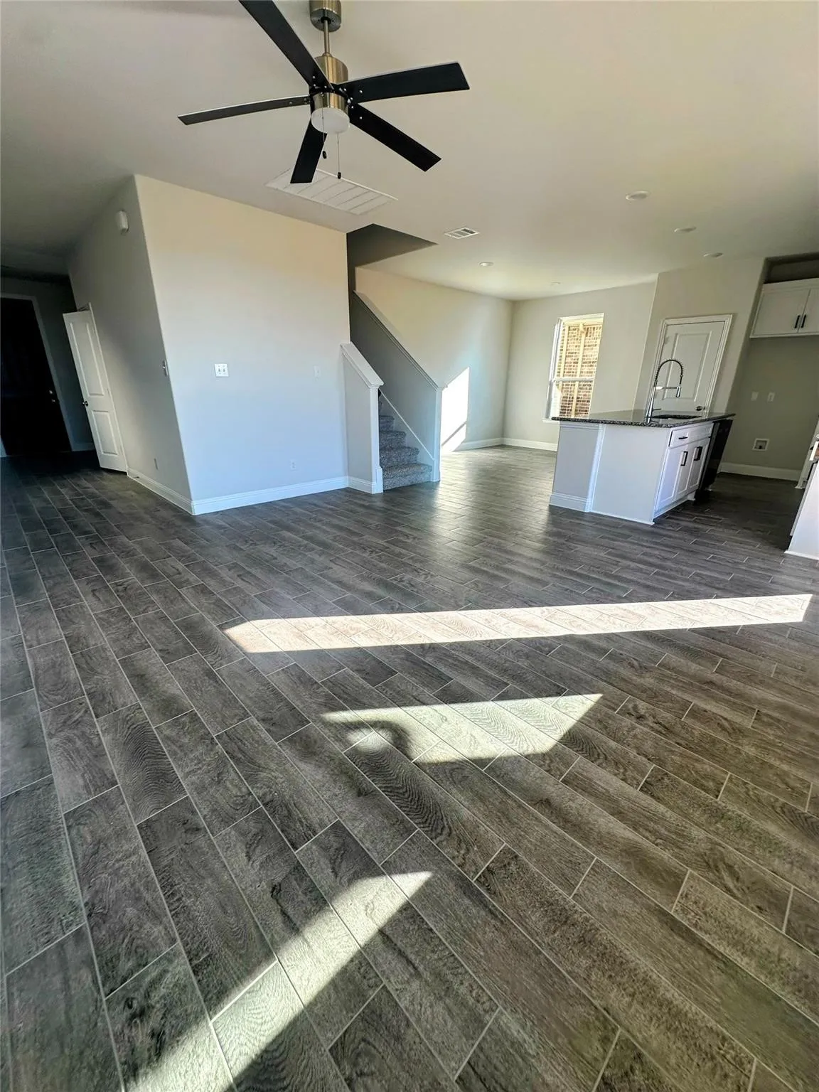 Open-concept living area featuring wood-finish tile flooring, a contemporary ceiling fan, and recessed lighting