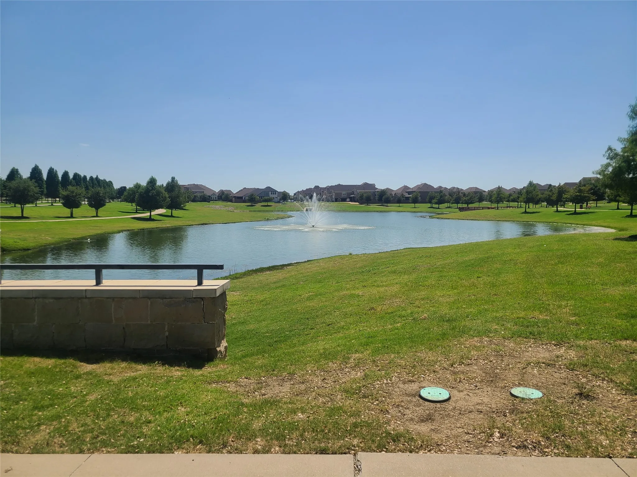 Expansive green space featuring a large pond with a central fountain