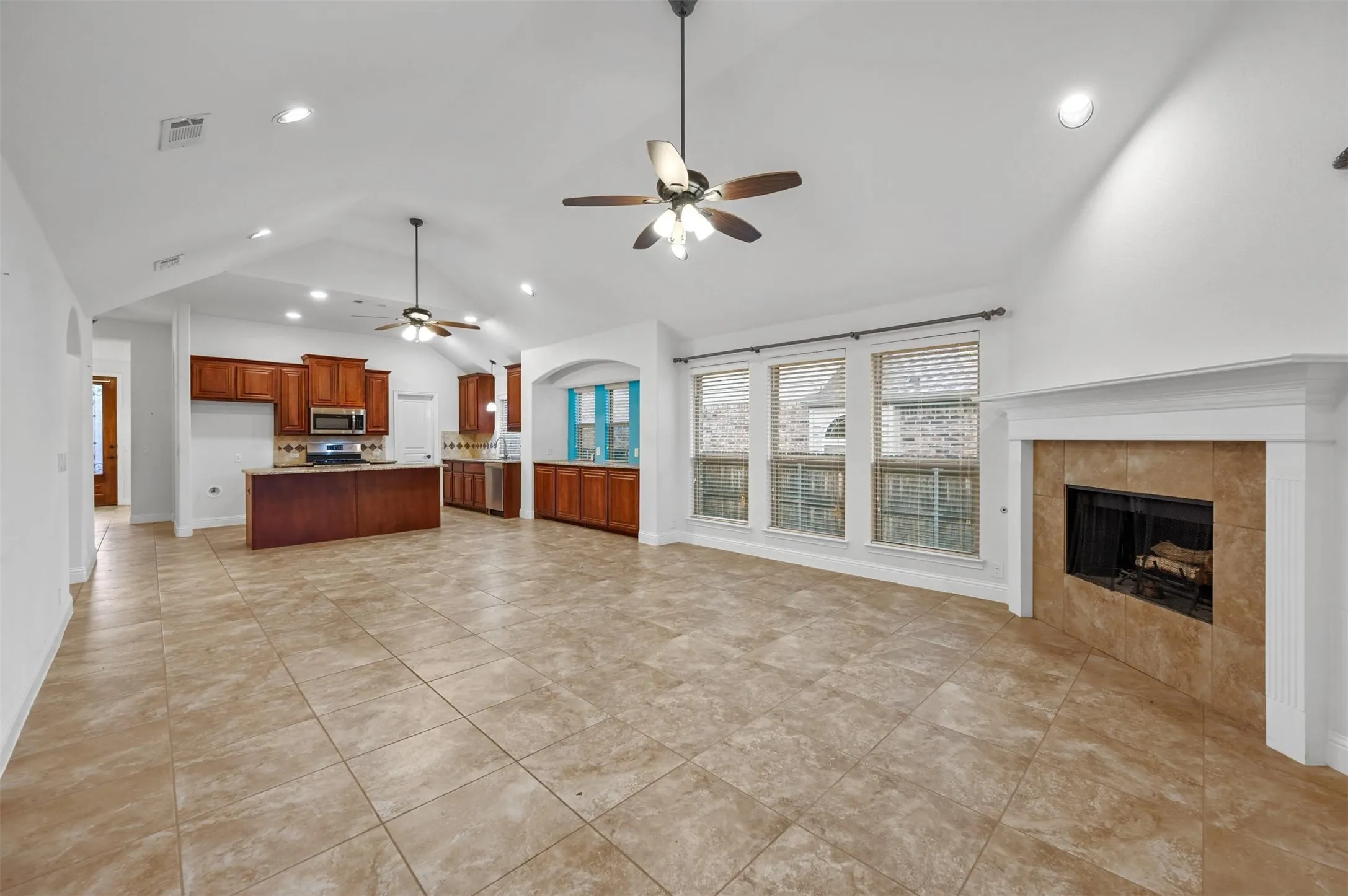 Spacious open-concept living area featuring a vaulted ceiling and tile flooring throughout