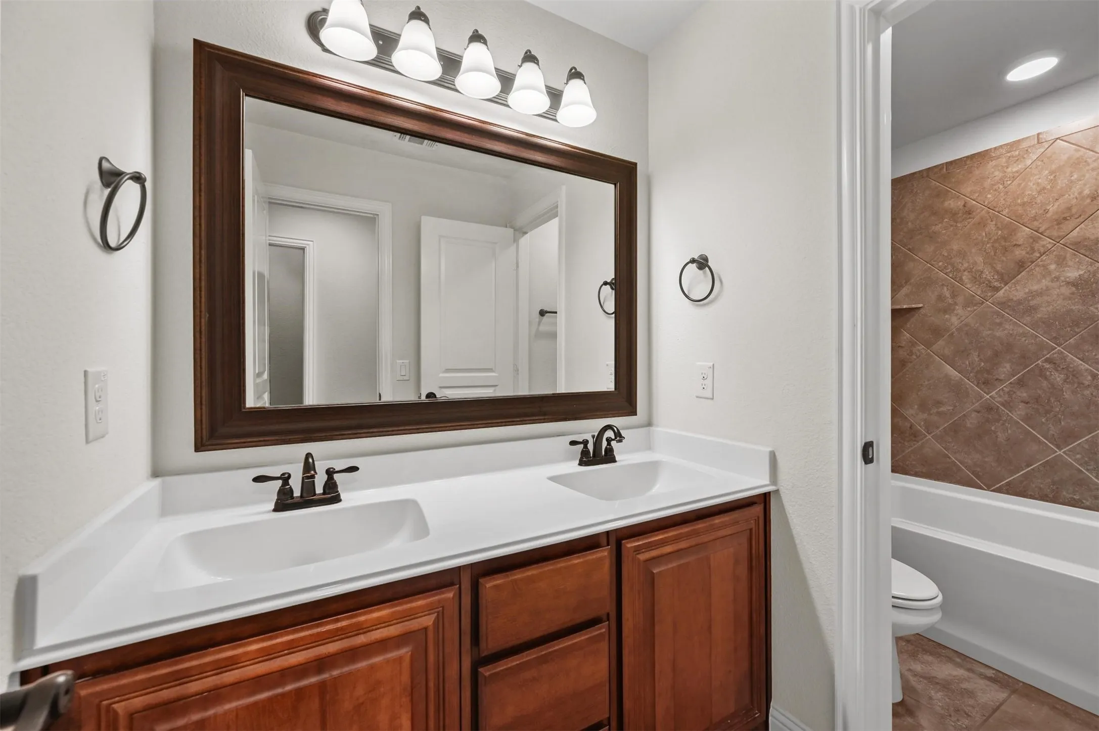 Bathroom #2
Hall bath downstairs Dual vanity featuring a wood-finish cabinet with white countertops, undermount sinks, and bronze-finish faucets