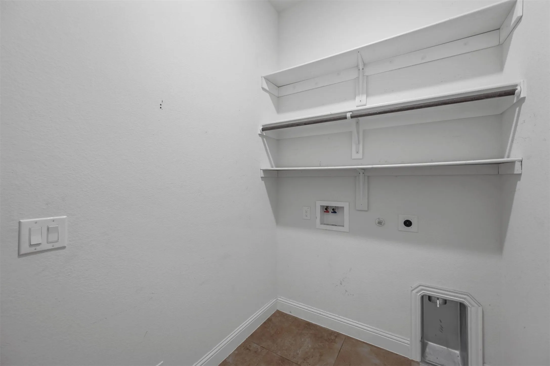 Dedicated laundry space featuring built-in shelving, a hanging rod, appliance hookups, and tiled flooring
