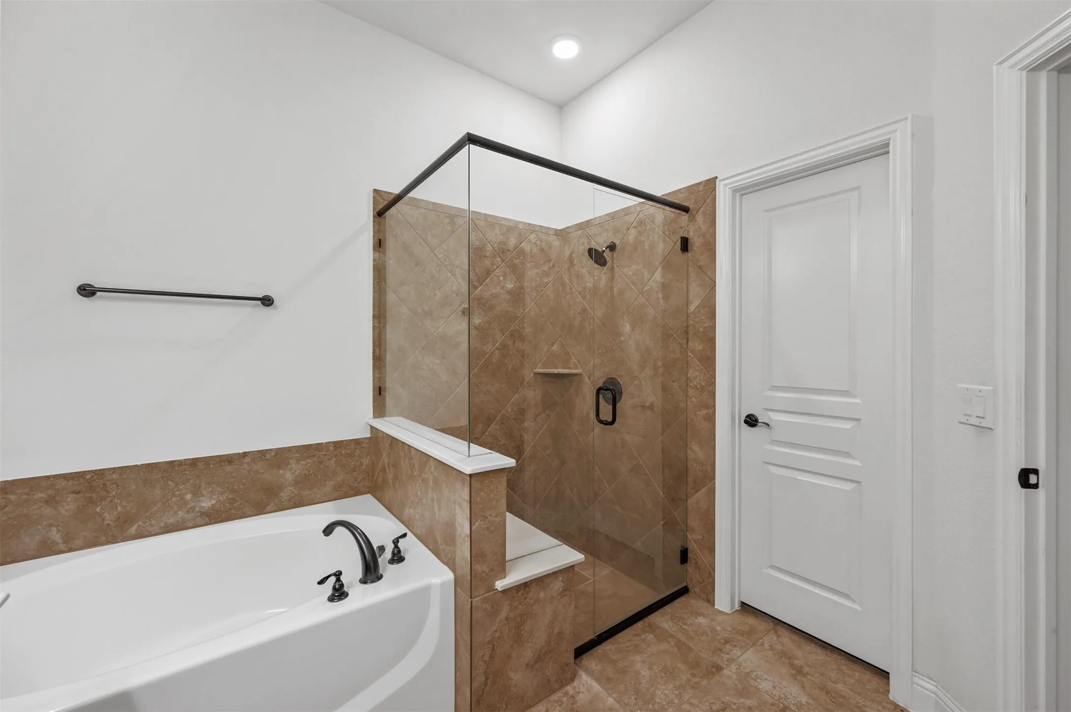 Shower with glass enclosure and tiled walls, featuring a built-in bench and recessed niche