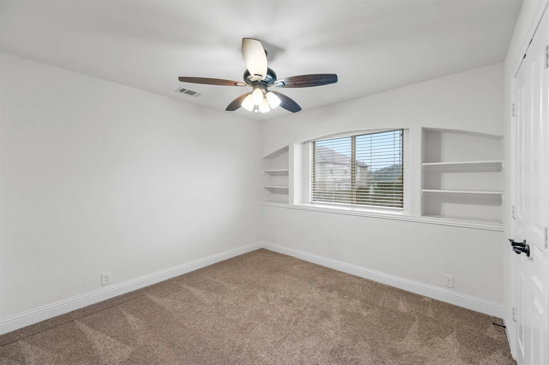 Bedroom #2
Recessed window with built-in shelving, complemented by a ceiling fan with integrated lighting, and neutral carpet flooring