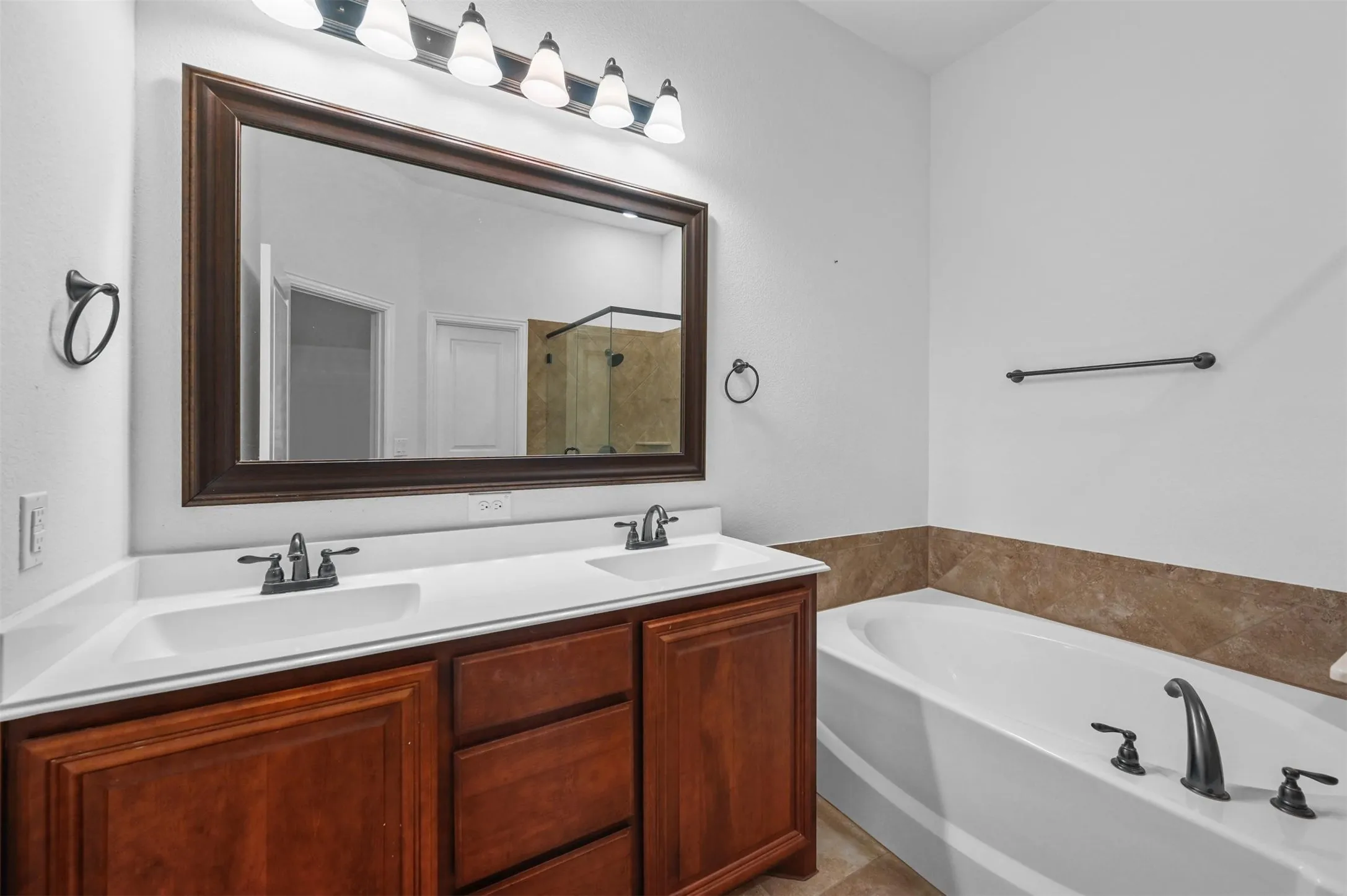 Dual vanity with cherry wood-finish cabinetry, white solid surface countertops, and integrated sinks