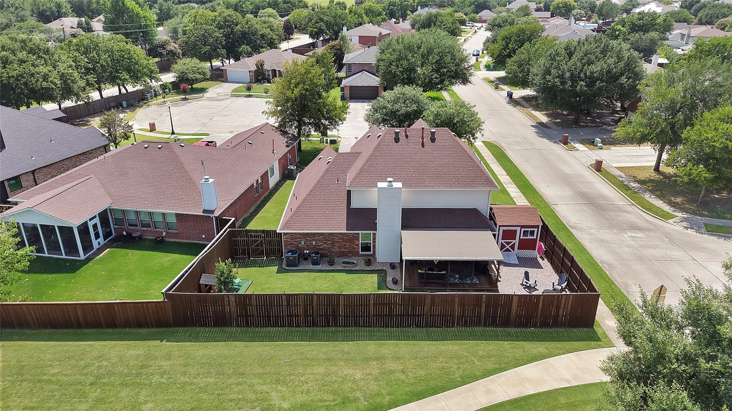 Expansive private backyard featuring a wood fence, a large deck with an awning, a paver patio, and a storage shed