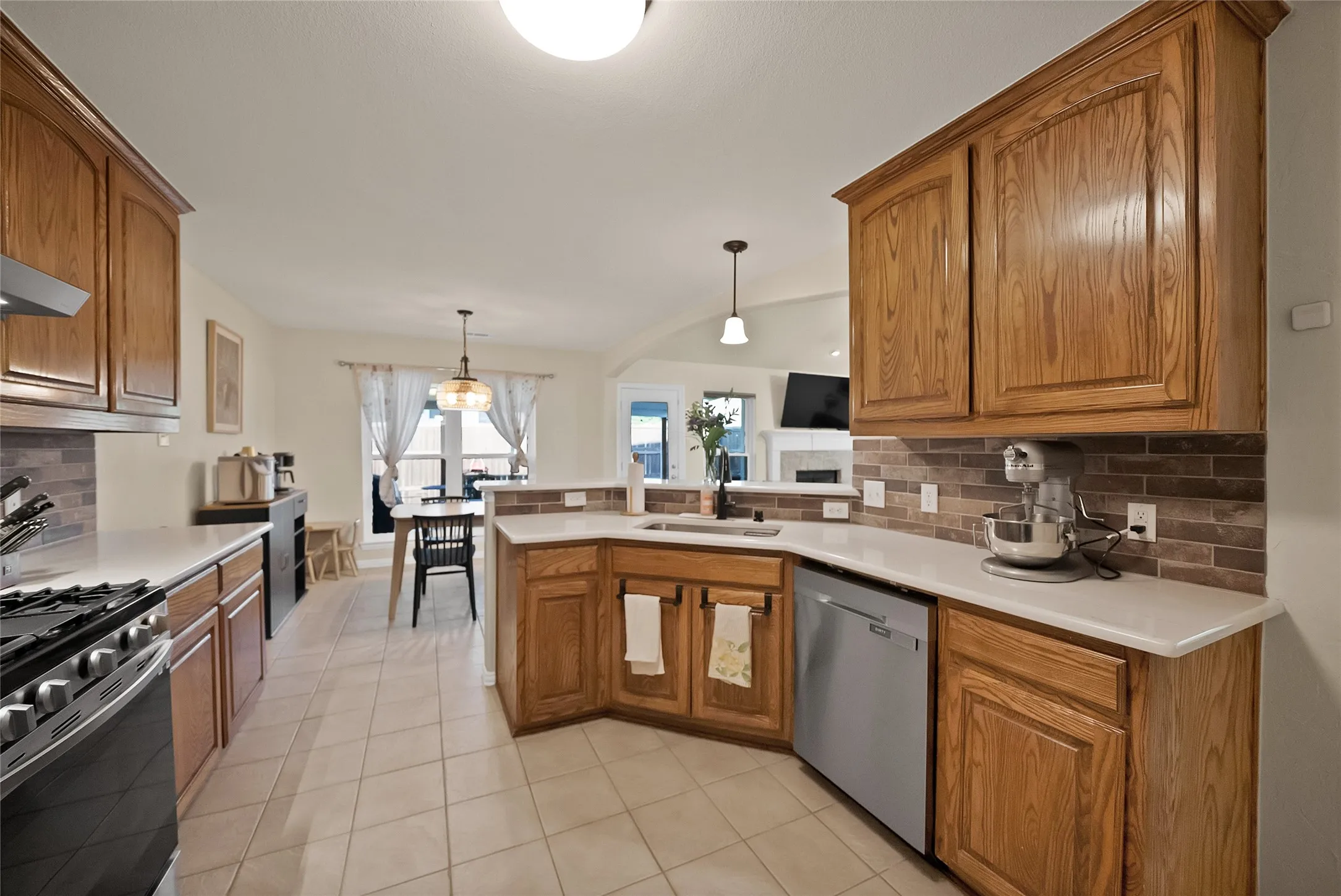 Kitchen featuring wood cabinetry, light-toned countertops, a tile backsplash, and stainless steel appliances