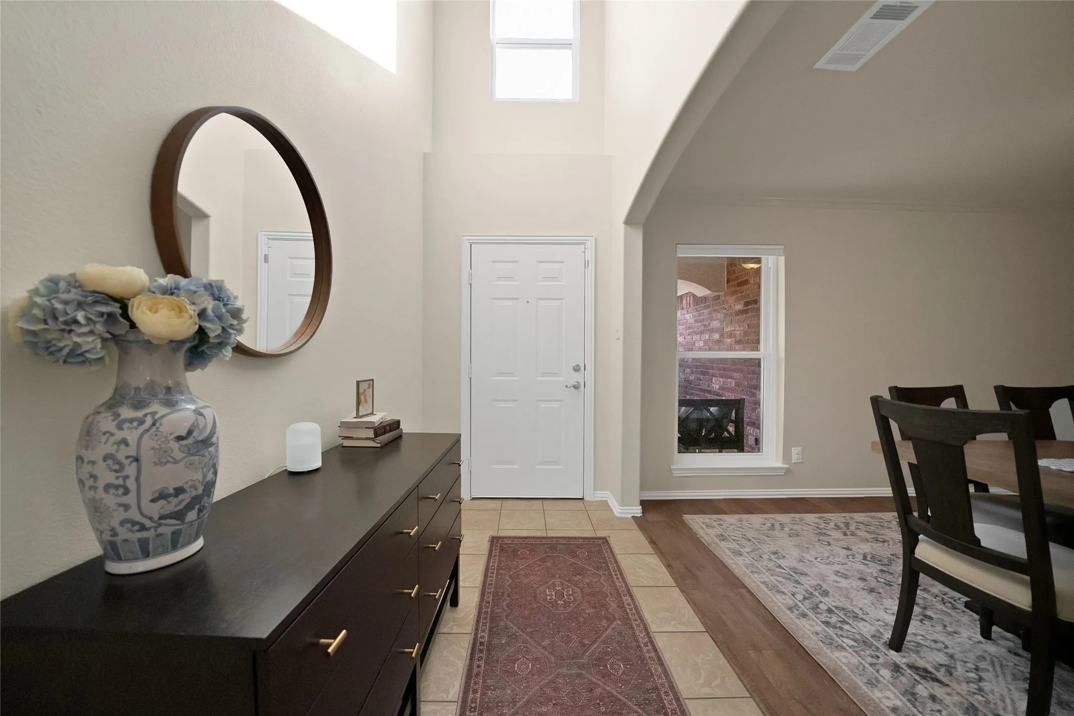 Entryway featuring a white paneled door, tiled flooring, high ceilings, and transom windows